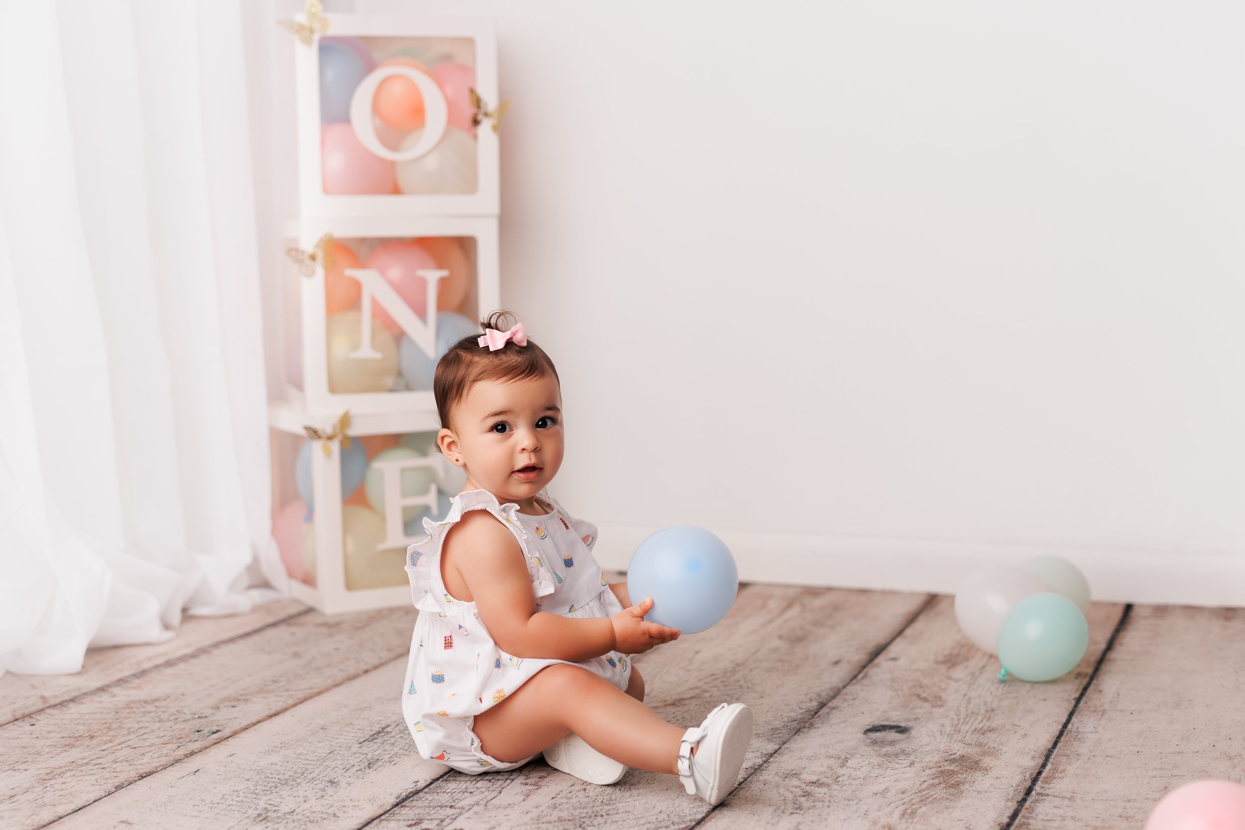  Baby girl plays on the floor of a New Jersey studio during her first birthday milestone photoshoot 