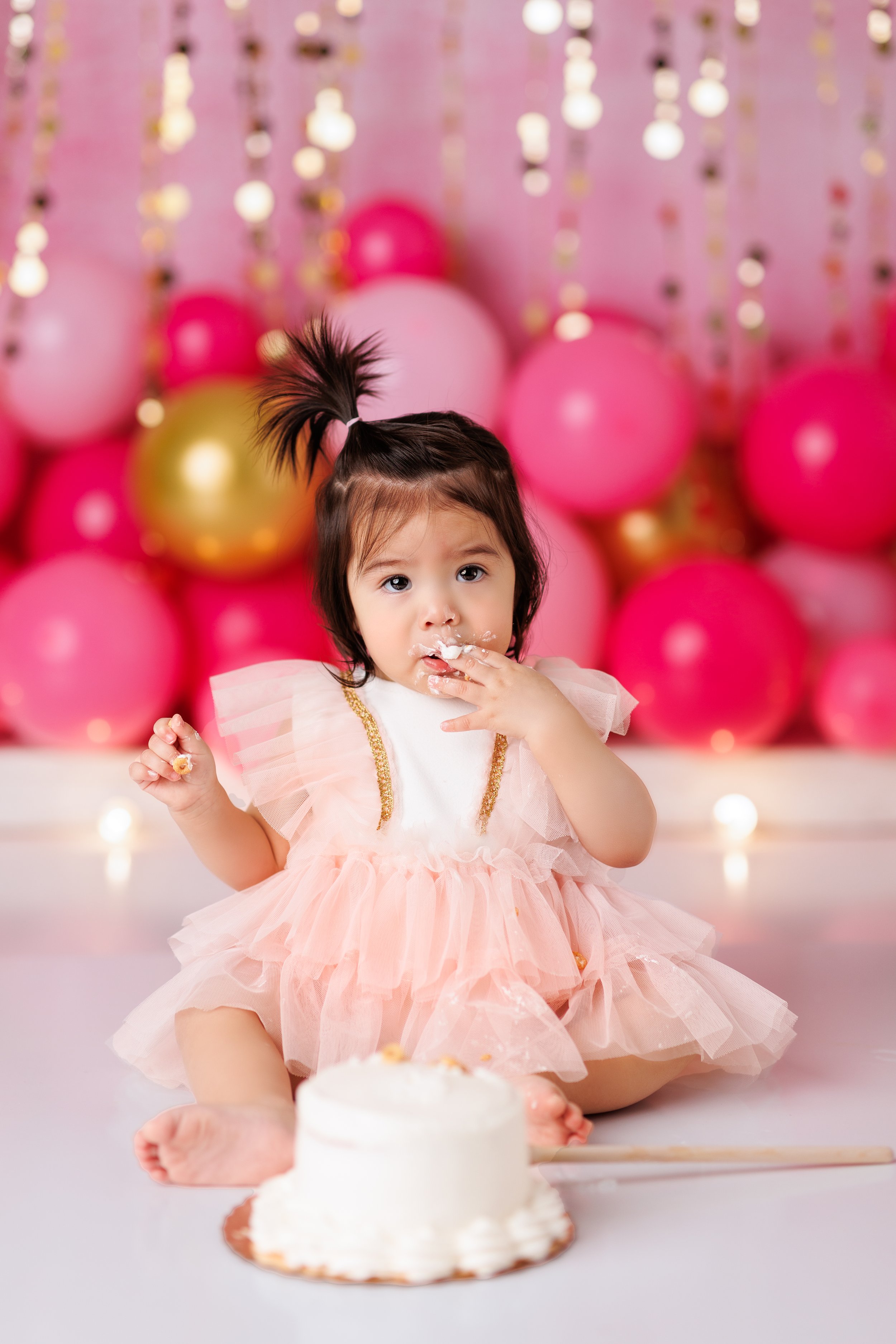  Baby girl in pink tulle dress tests her cake during her first birthday photography session in New Jersey 