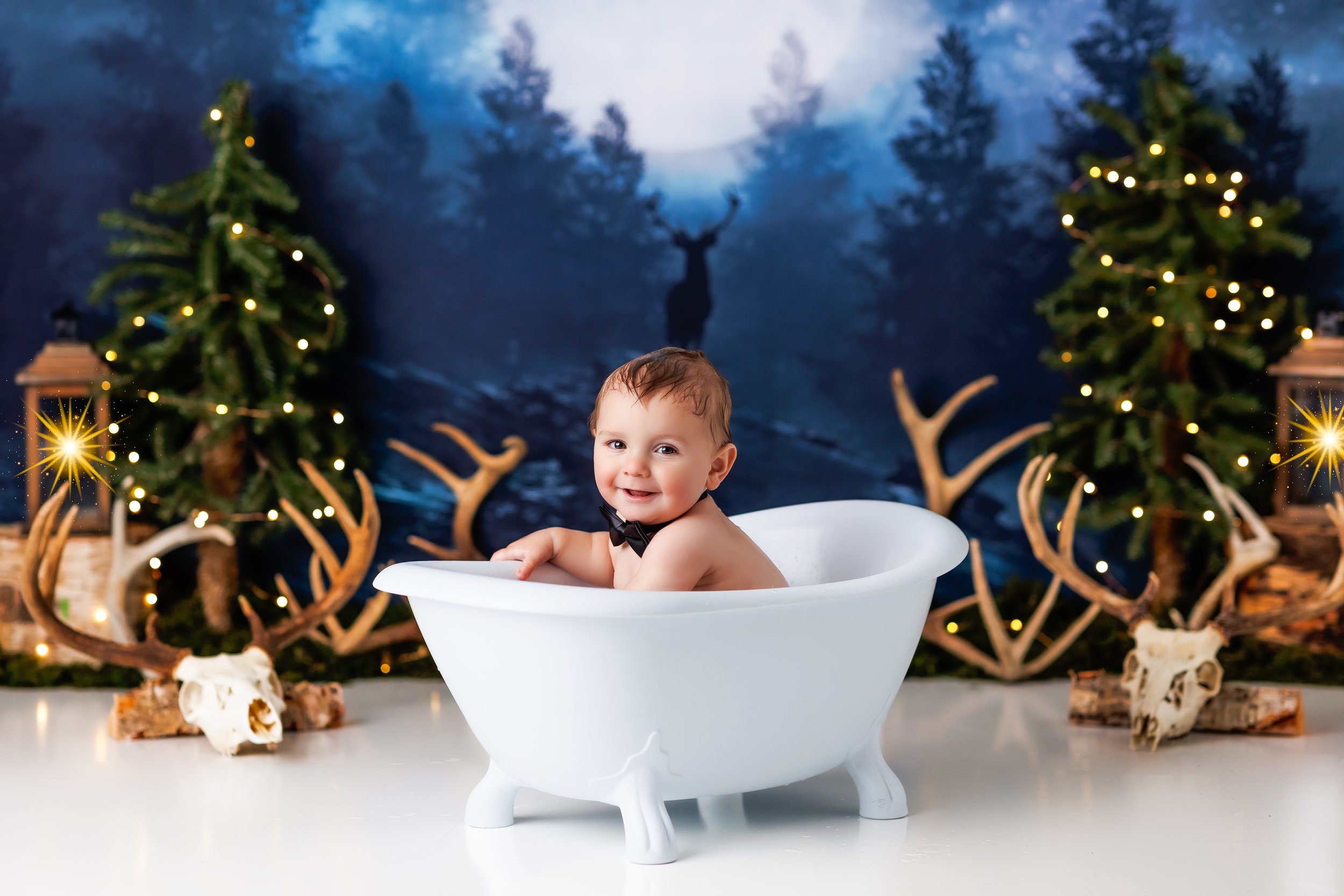  One-year-old boy in tub with a forest and antlers backdrop  