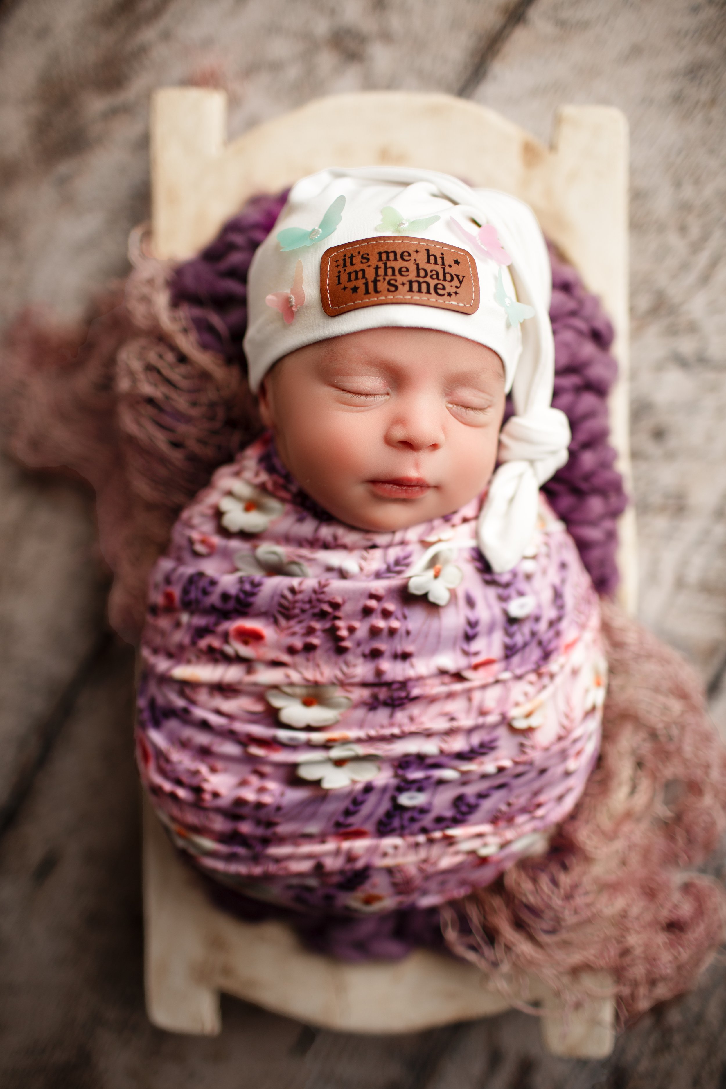  Infant in purple floral wrap and monogrammed beanie 
