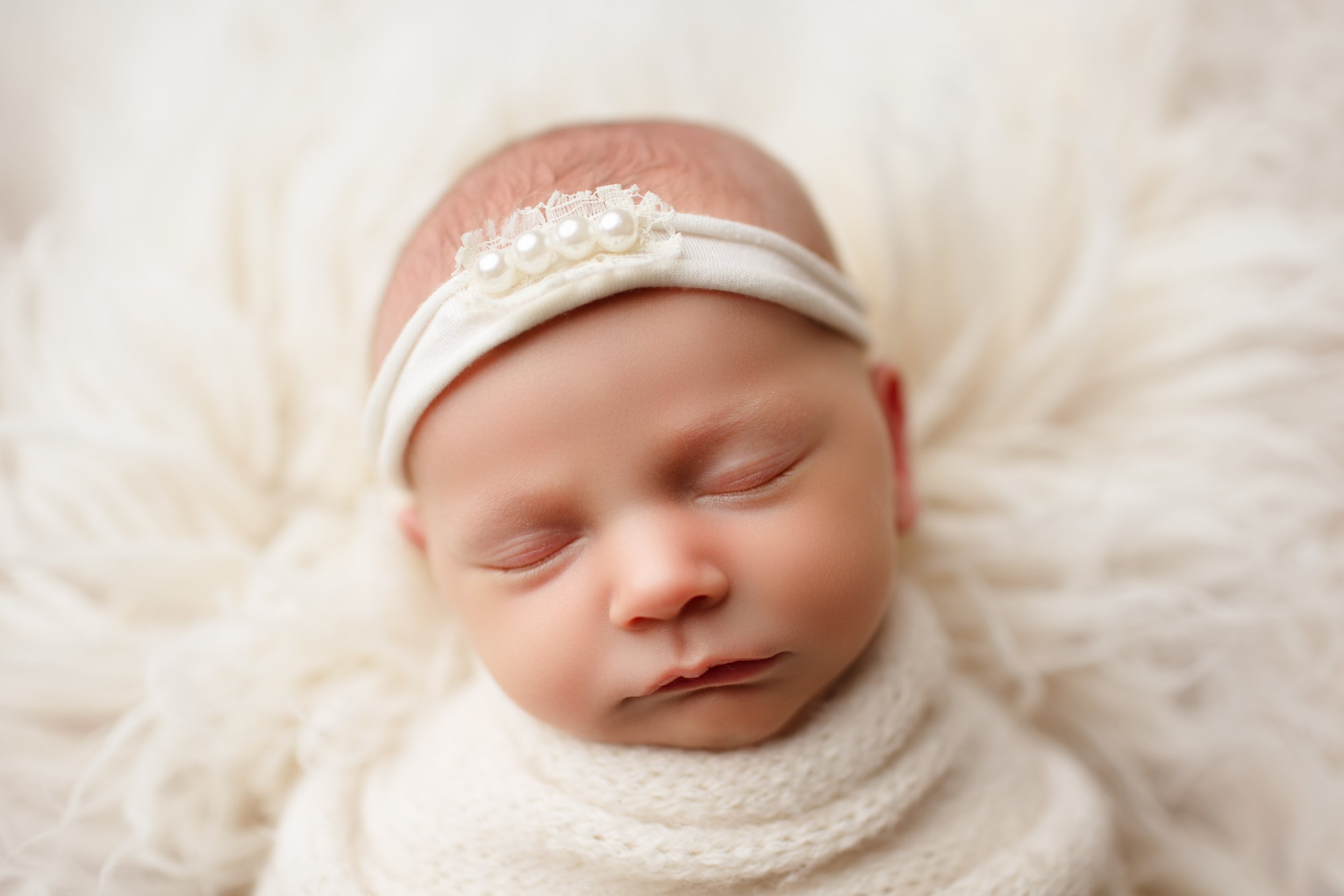  Sleepy baby girl in a white swaddle and headband 