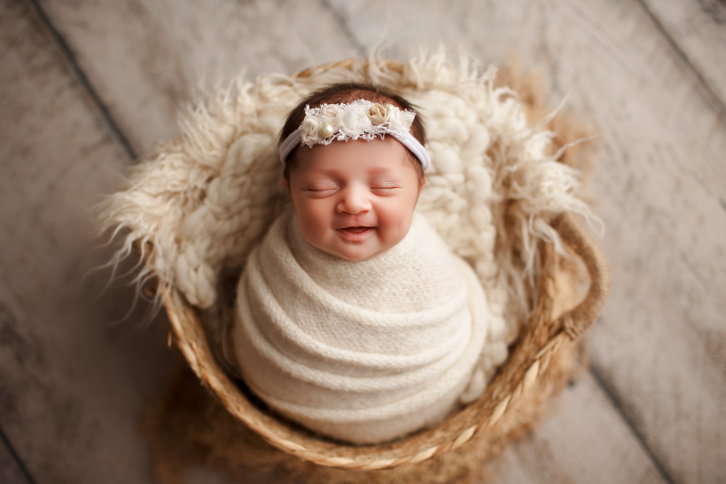  Swaddled baby in basket gives a sleepy smile during her newborn photography session in NJ 