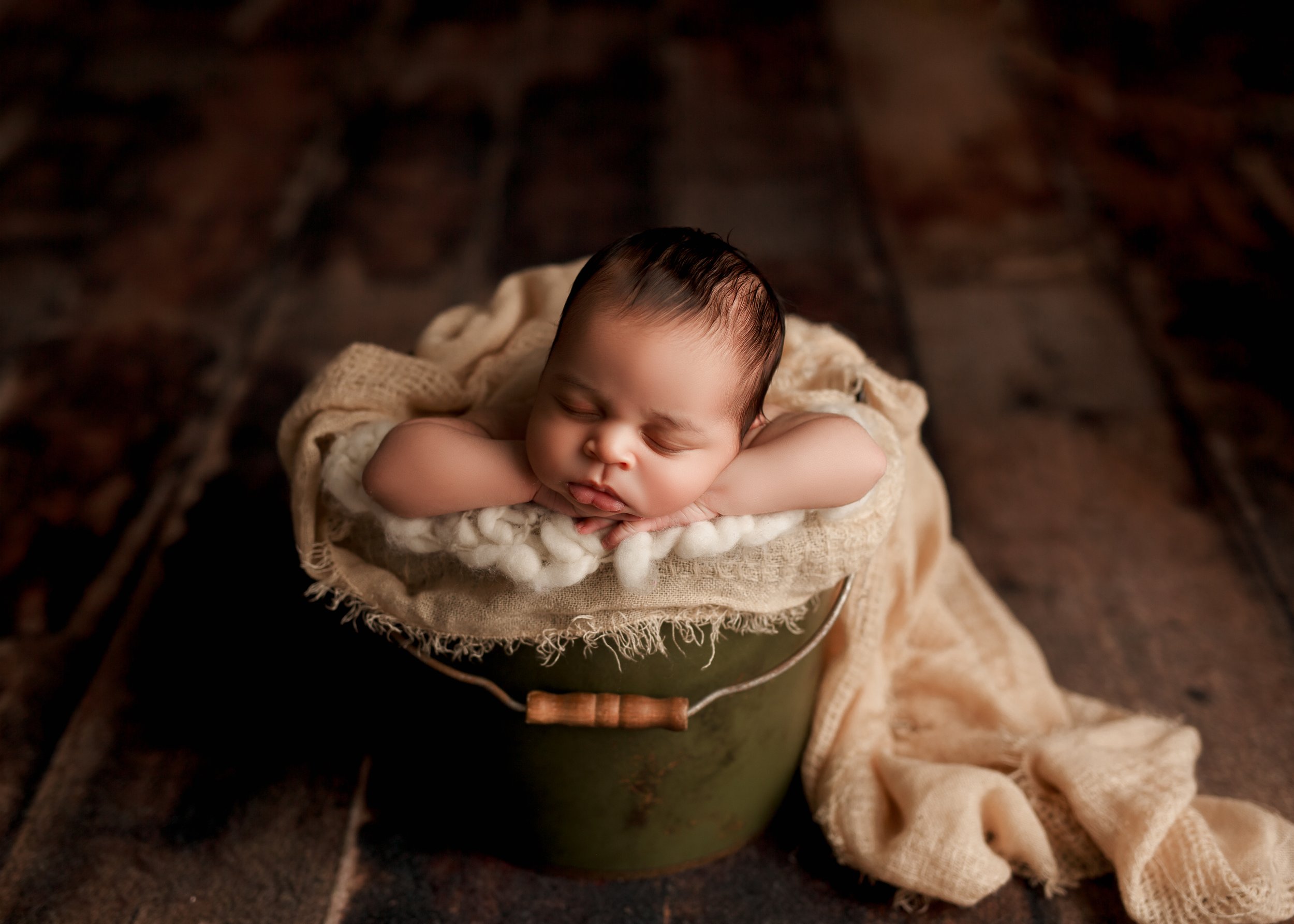  Newborn asleep in cushioned antique bucket 