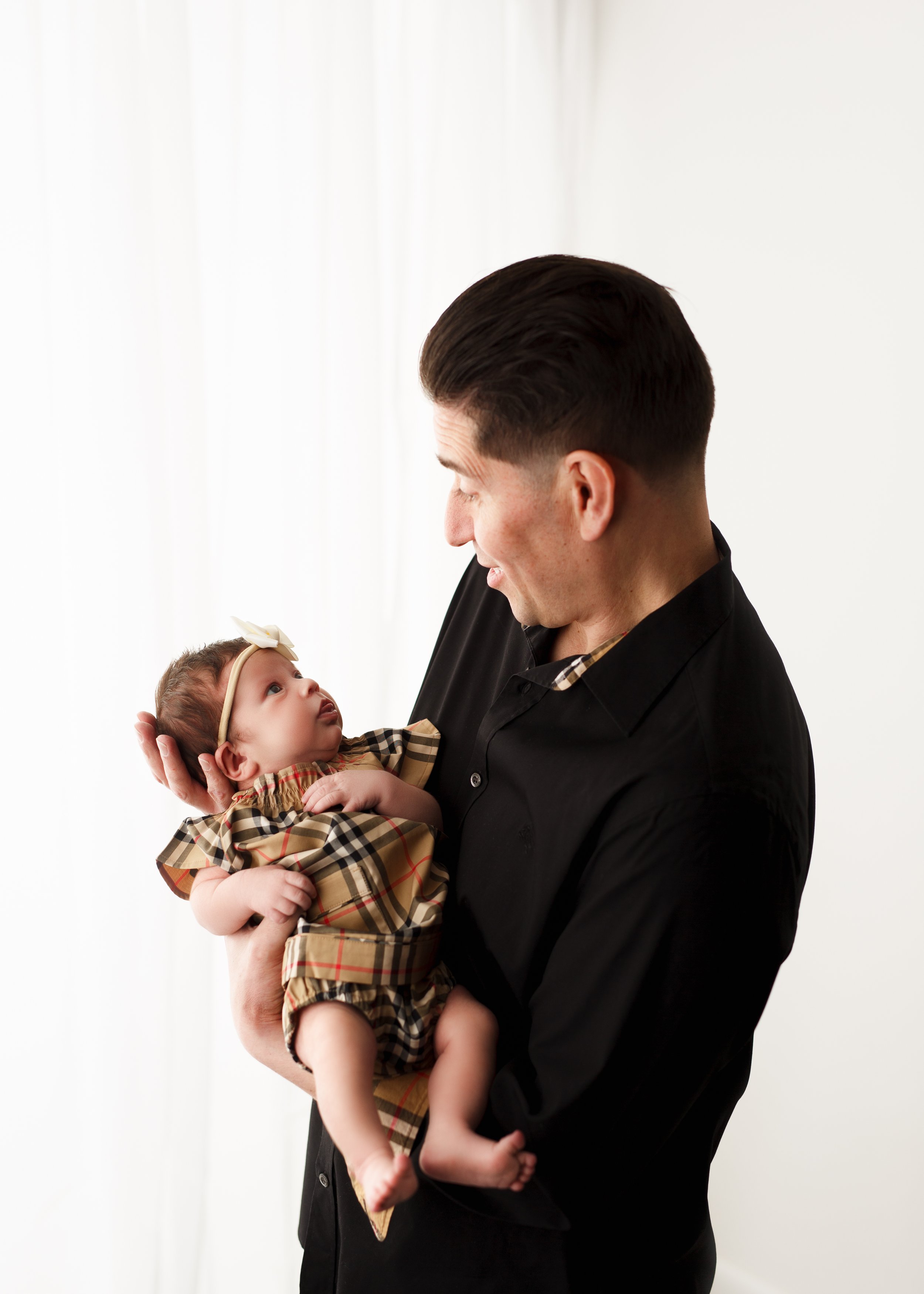  New daddy and his infant daughter look at each other in a sweet exchange in a professional newborn photo studio serving the NJ/NY/CT Tri-State area 