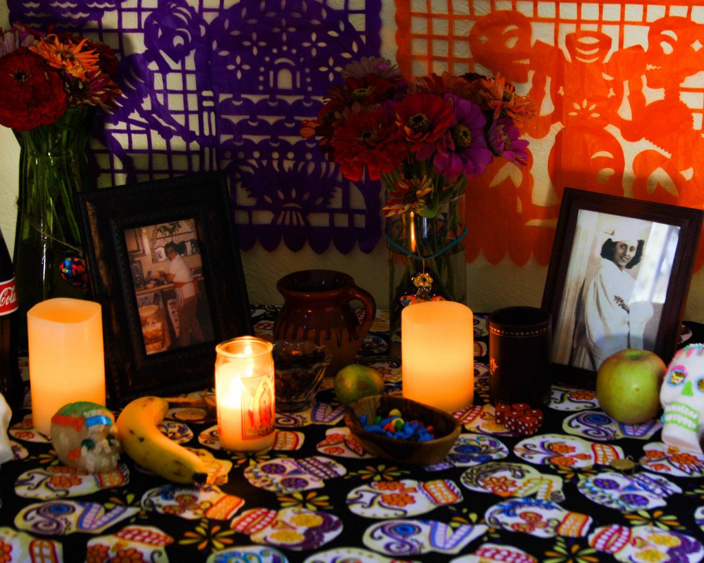 Nicole’s altar includes homegrown zinnia flowers, Day of the Dead food-themed papel picado , and photos of her grandmother — one from her graduation because she loved to study, and the other in the kitchen, which shows her love for entertaining and baking. Photo courtesy of Flan and Apple Pie.