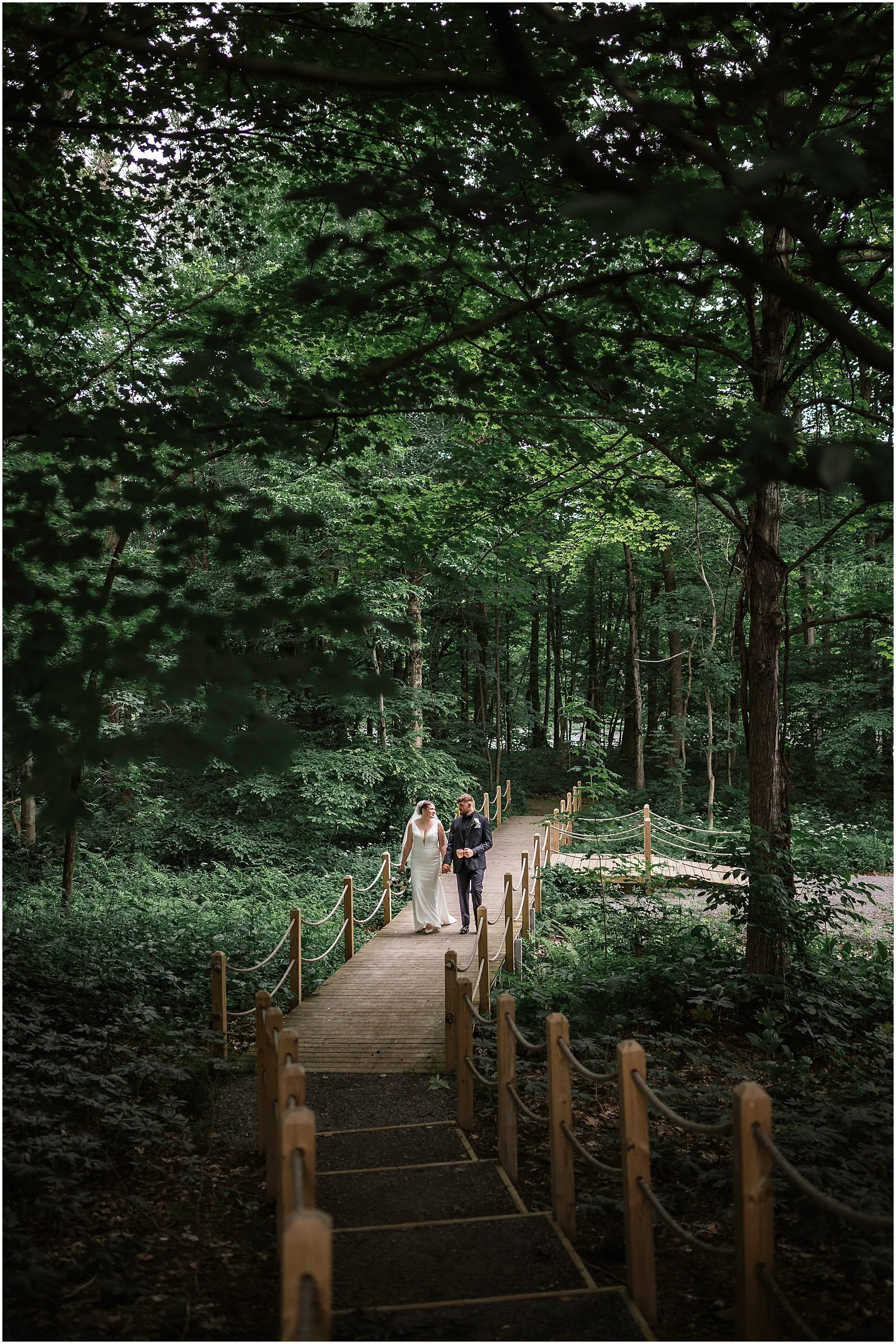 Upstate New York bride and groom walking on a wooden bridge together after their spring wedding in the Catskills.
