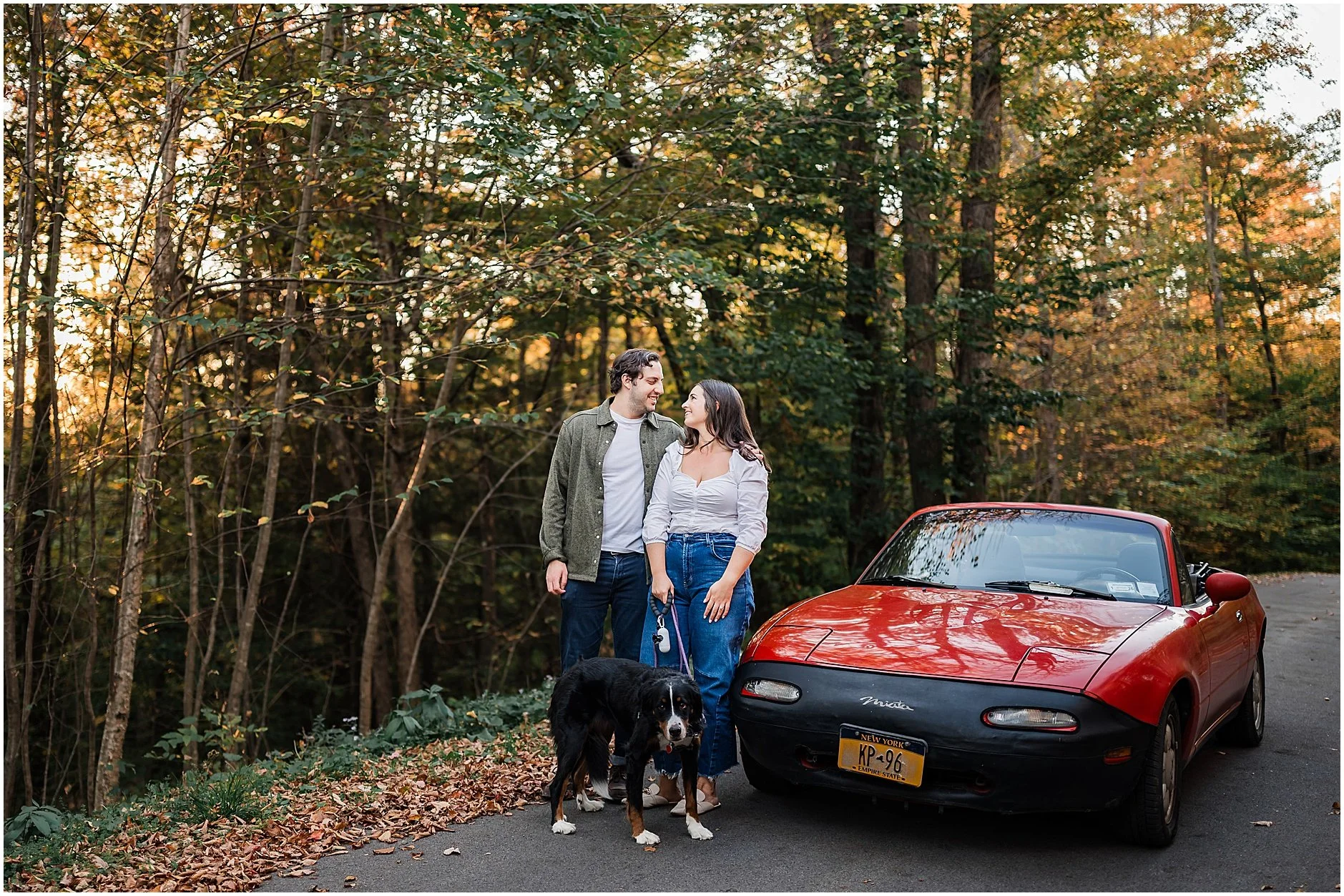 Playful engagement photo with vintage red convertible in Upstate New York
