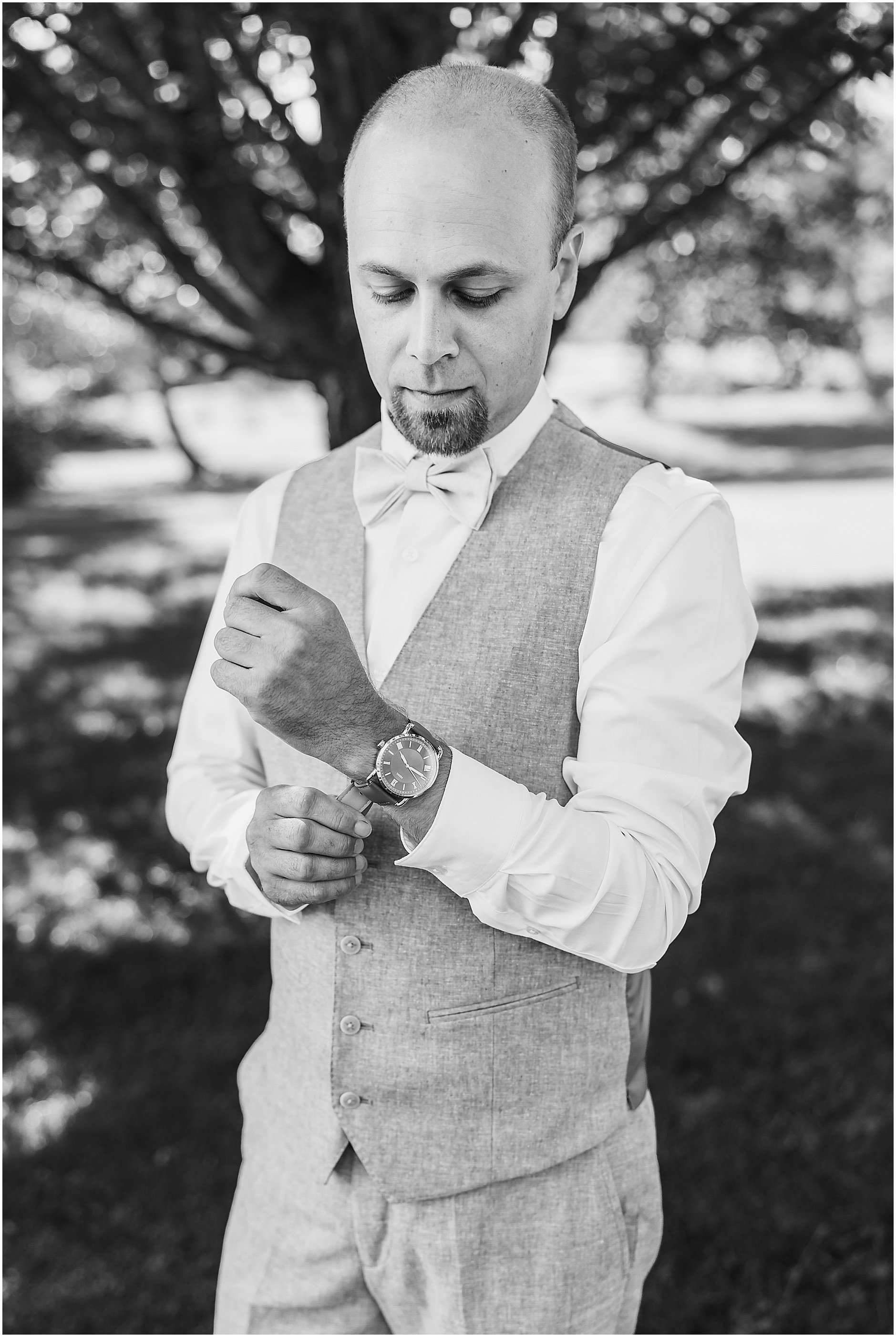 Black and white image of the groom putting his watch on as he gets ready for the ceremony at The Inn at West Settlement