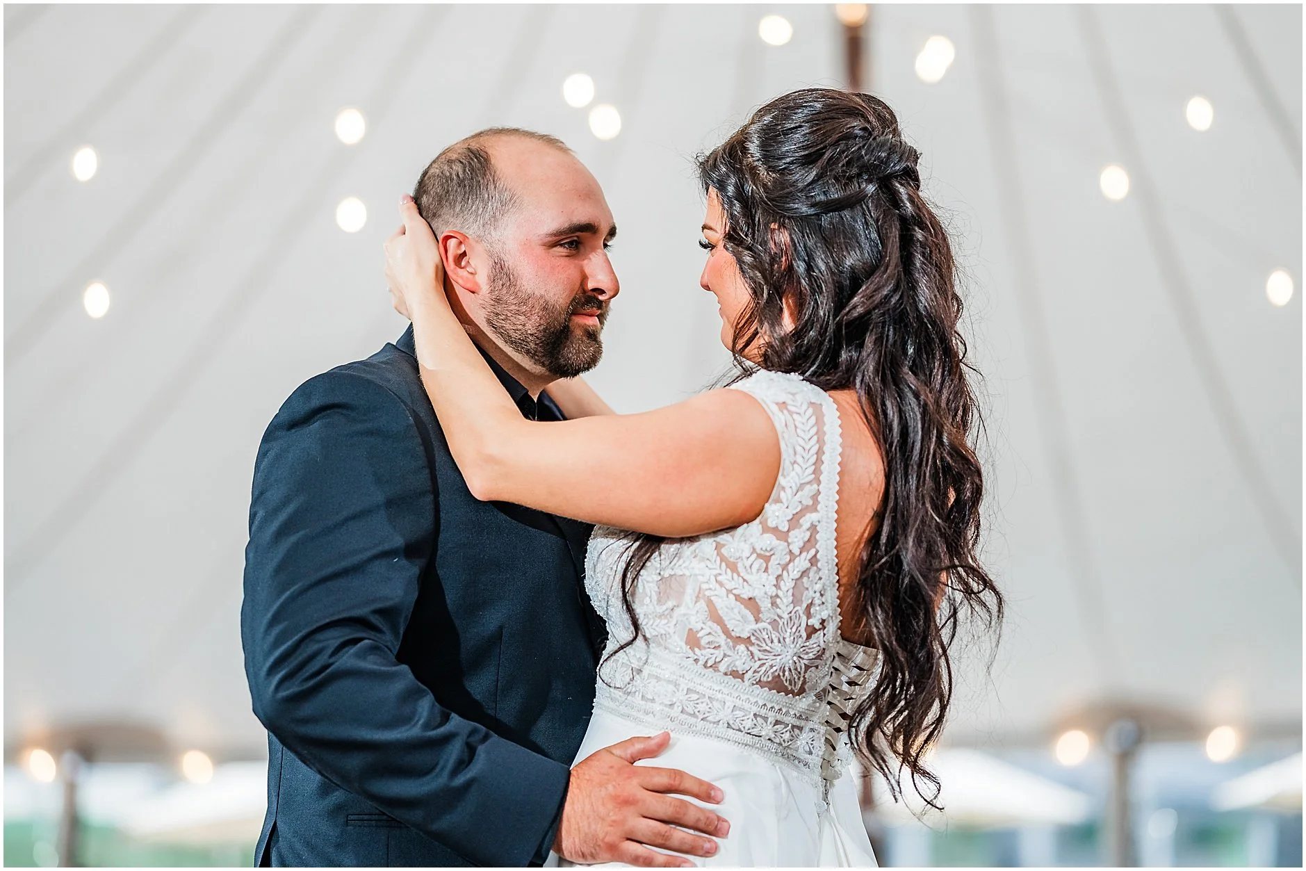 Intimate image of bride and groom during their first dance as husband and wife under white tent with fairy lights