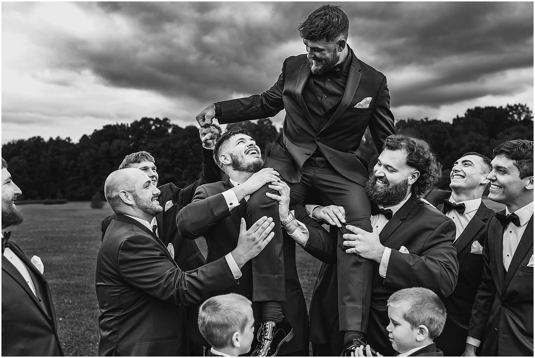 Black and white image of the groom being carried by the groomsmen at a wedding in the Catskills.
