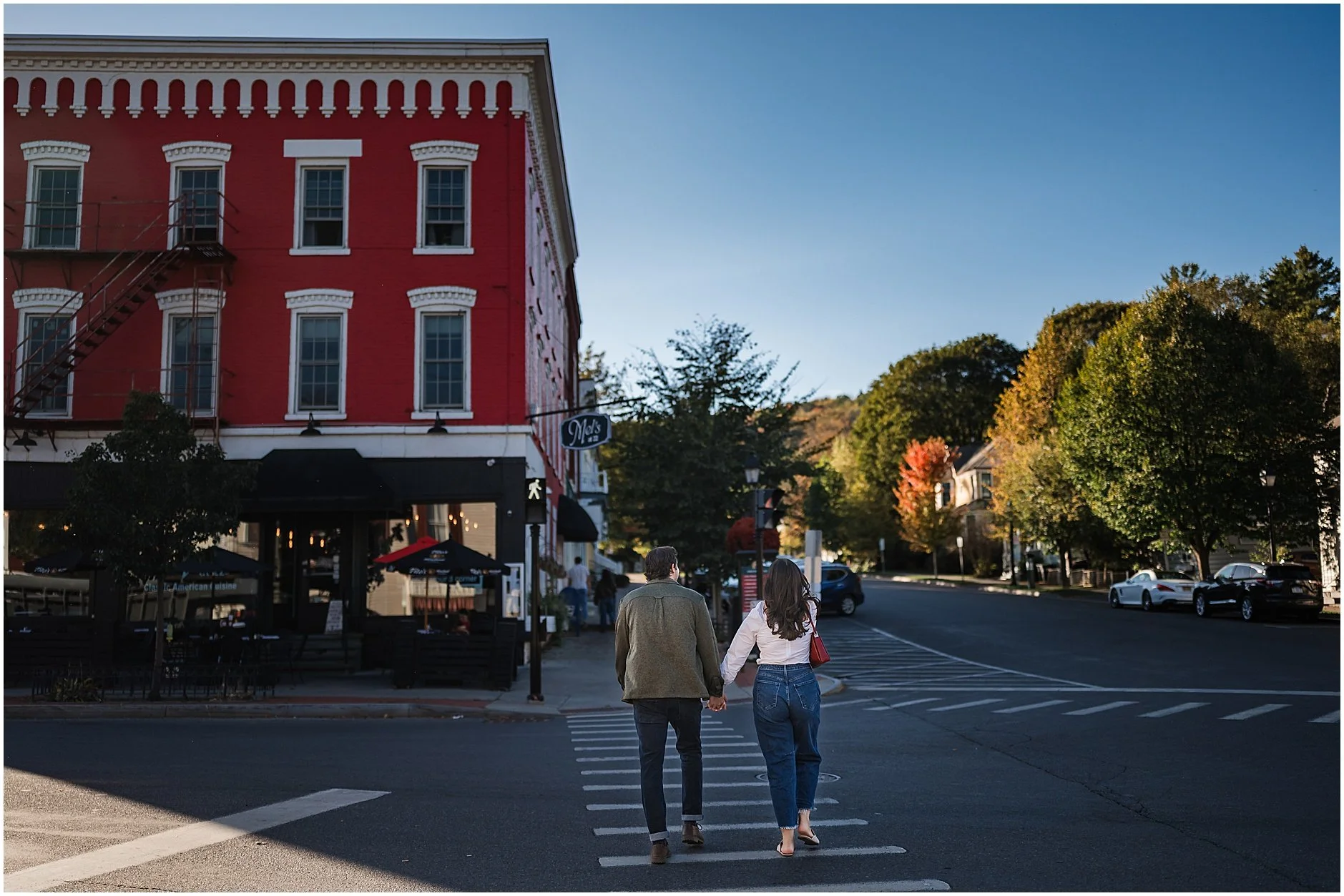 Couple walking in a crosswalk on their way to Mel's 22 during their engagement session in Cooperstown, NY