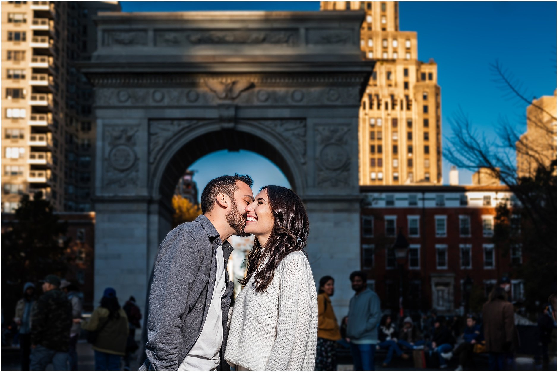 Groom to be giving his bride to be a kiss on the cheek while she smiles big during Soho NYC engagement session