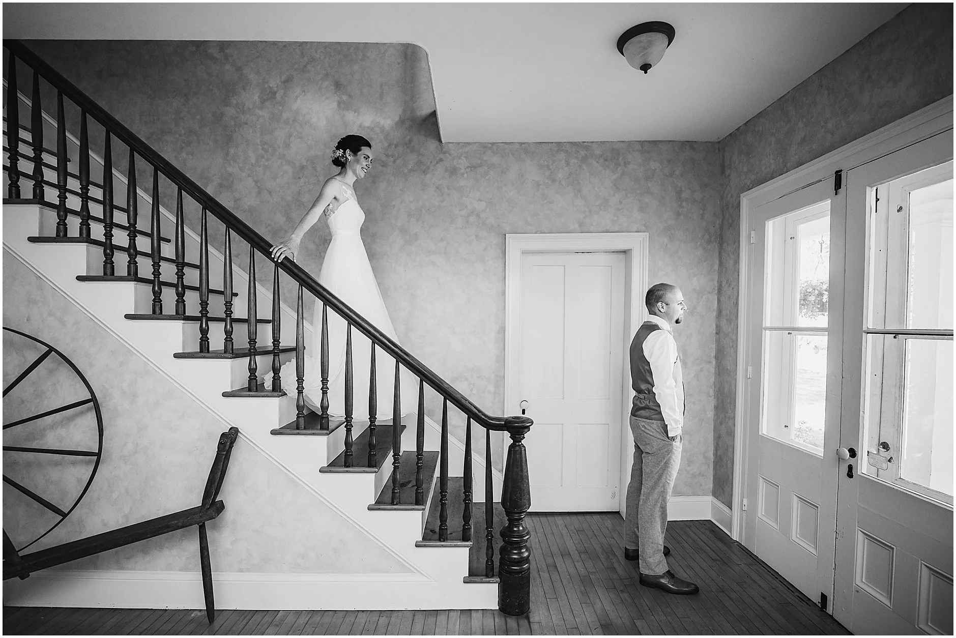 Black and white image of bride walking down the stairway to her groom for the first look in Upstate New York