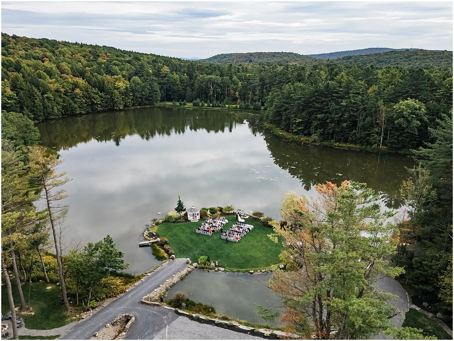 Aerial shot overlooking waterfront wedding ceremony at The Rosemary at Spano Lake in Cooperstown New York