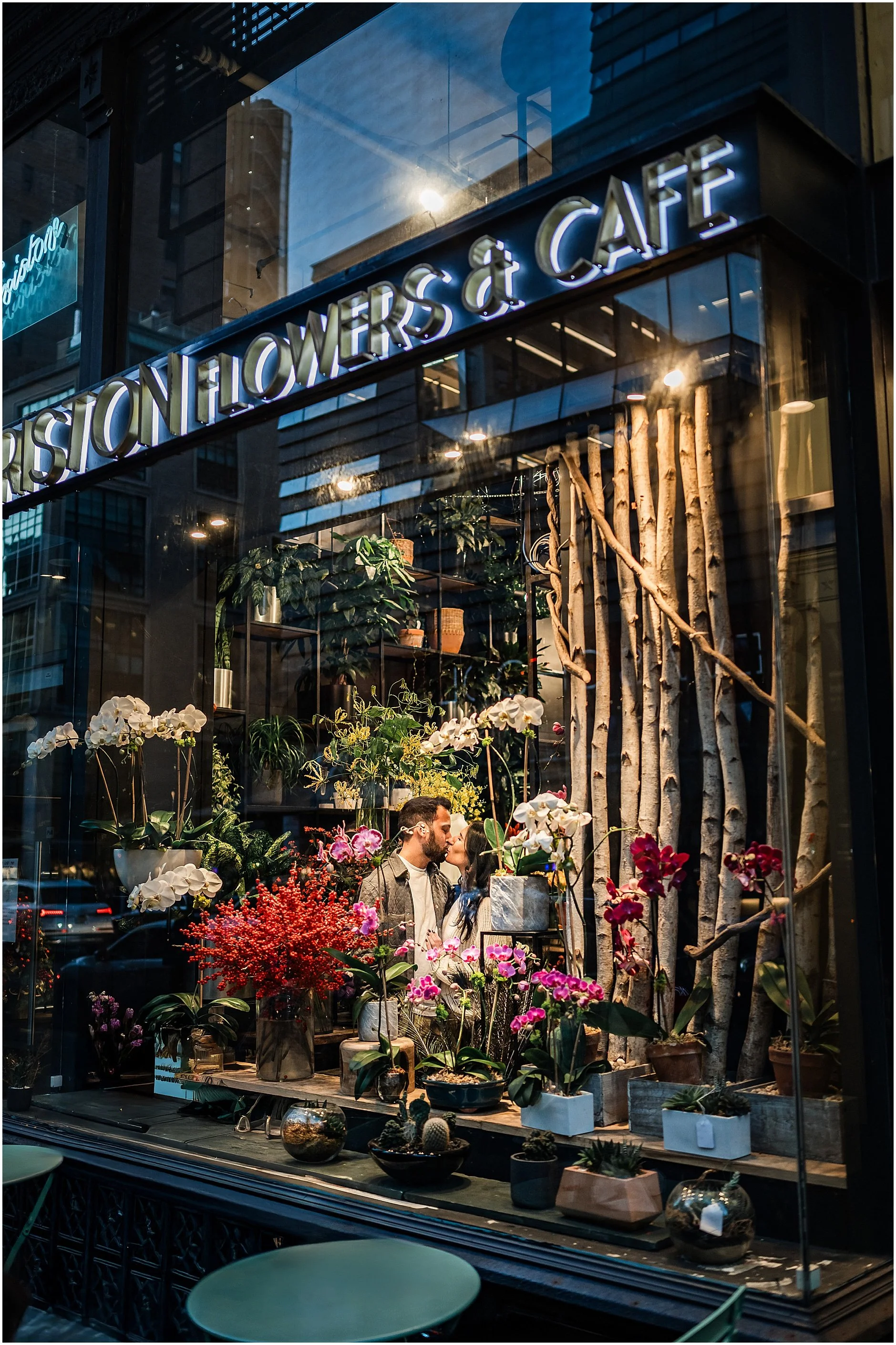Couple sharing a kiss in the window during their engagement session at a cozy Soho coffee shop