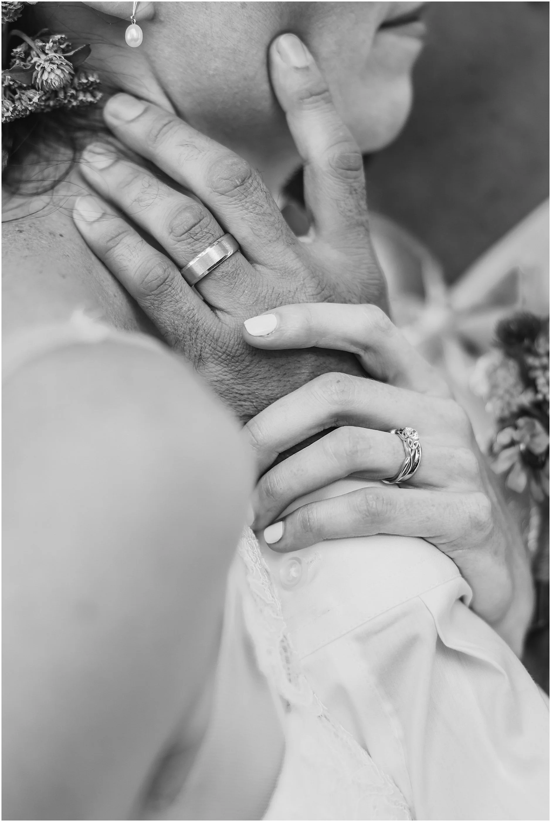 Black and white close up image of the bride and groom's hands with their wedding bands