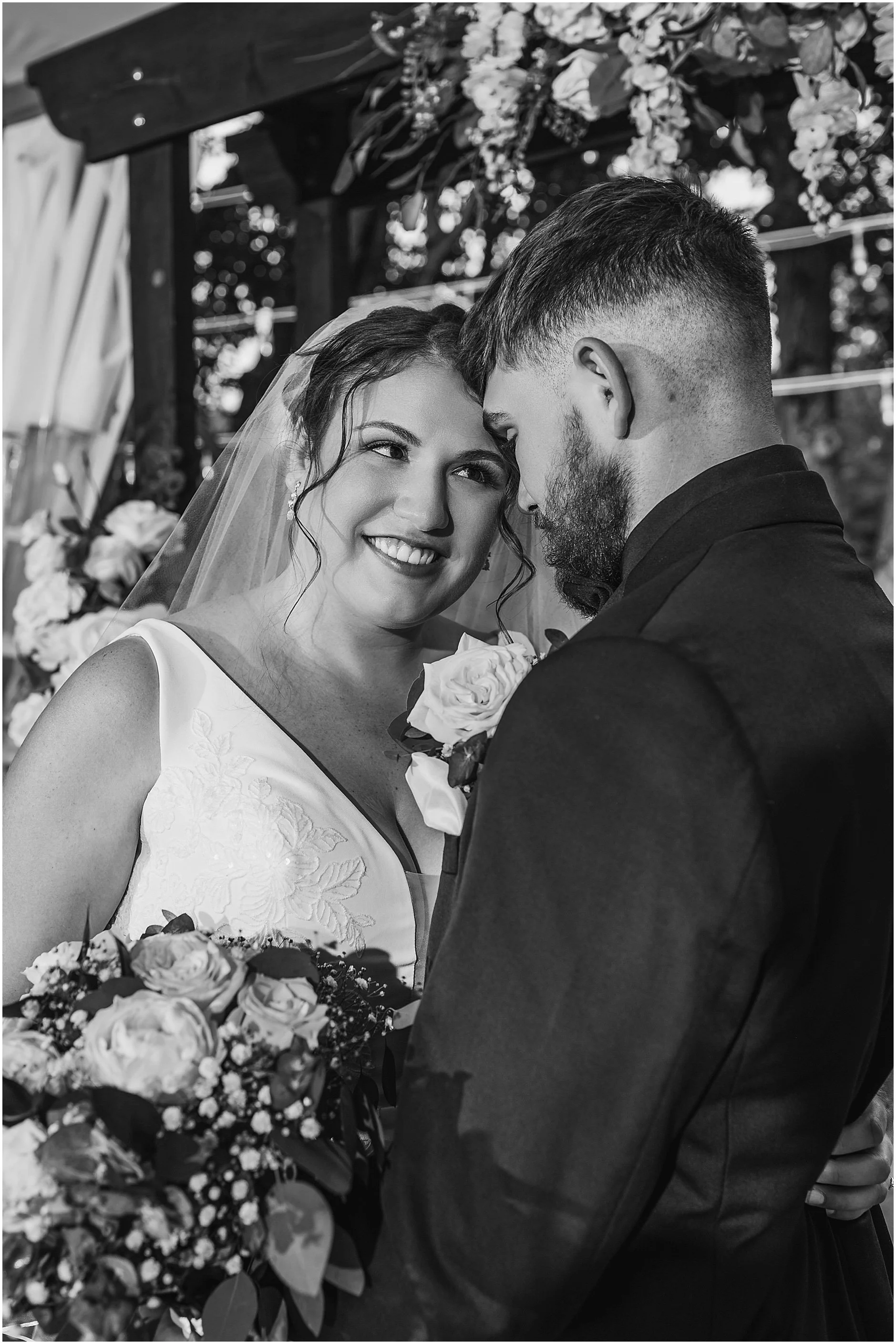 Black and white photograph of an Upstate New York bride looking at her groom.