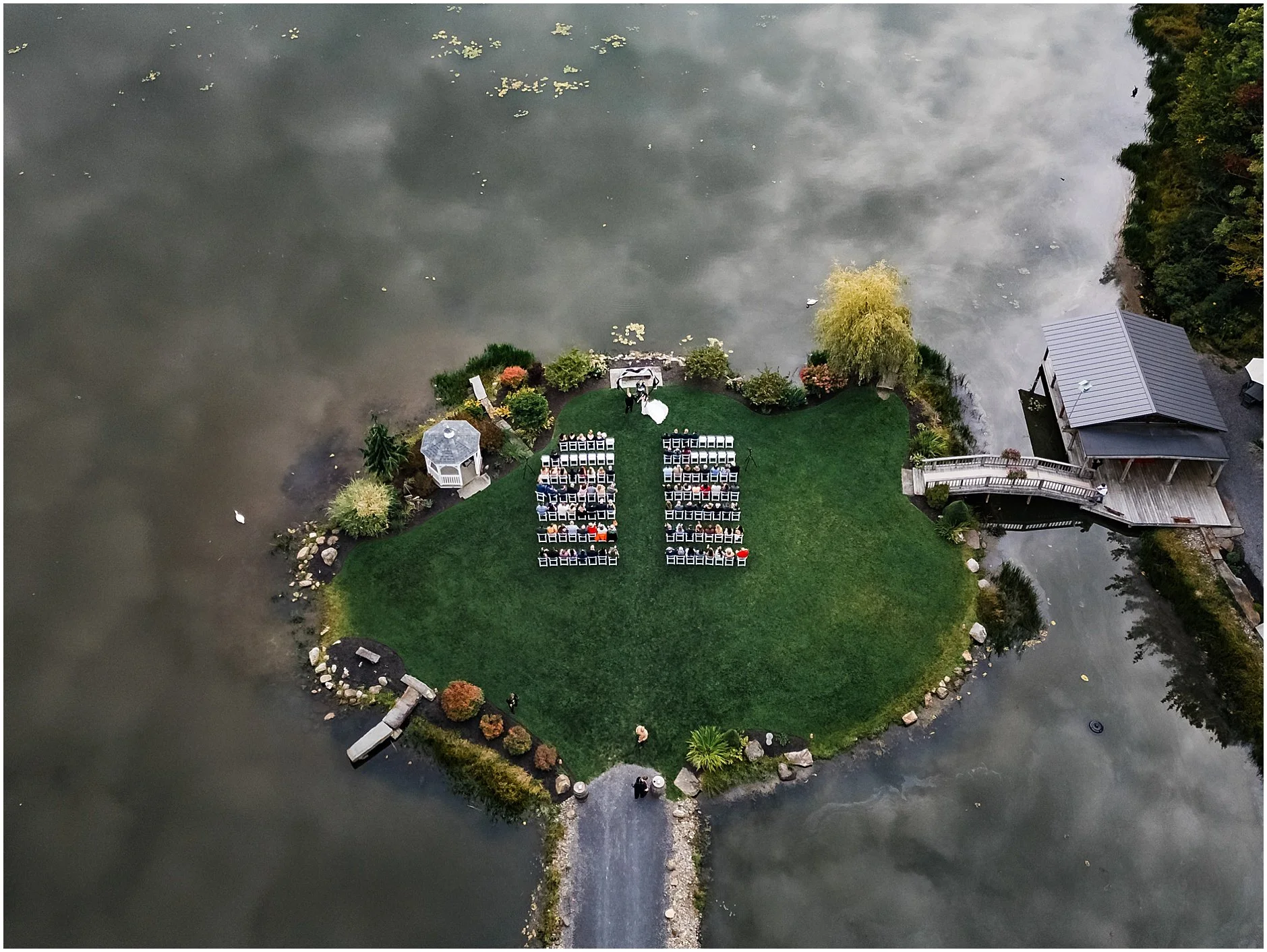 Drone shot from above wedding ceremony surrounded by water at The Rosemary at Spano Lake in Cooperstown