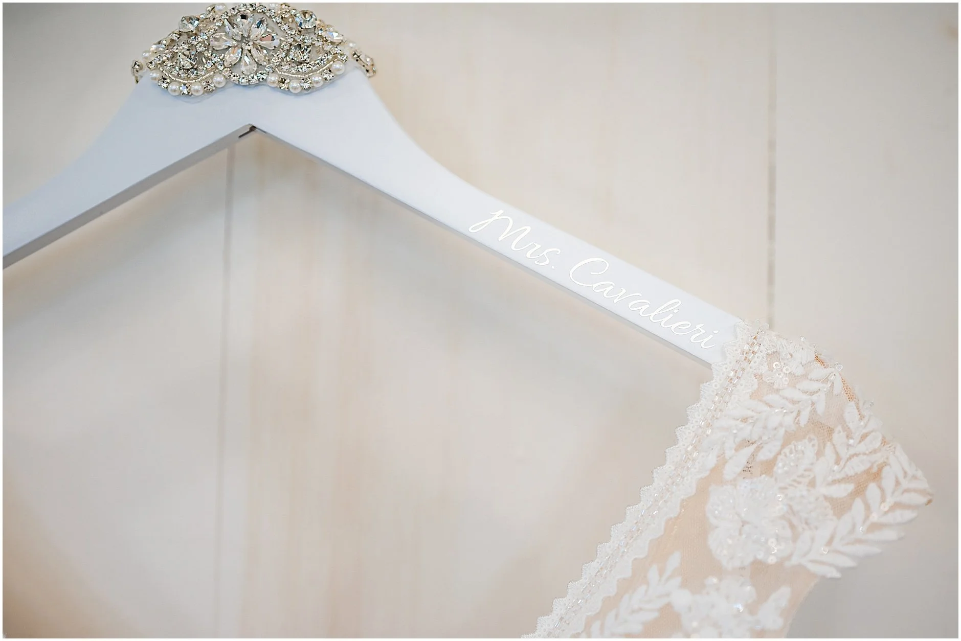 Detail shot of hanger with bride's last name holding wedding dress
