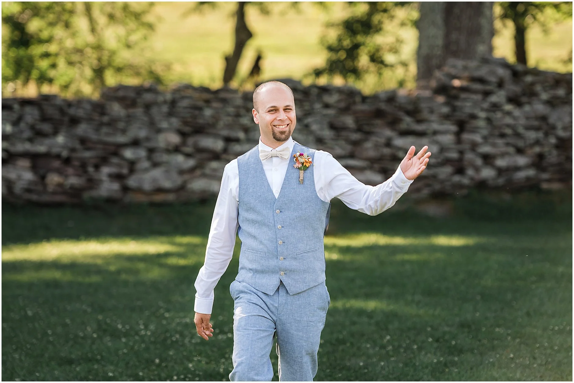 Groom smiling and waving as he walks down the aisle at his wedding in the Catskill Mountains