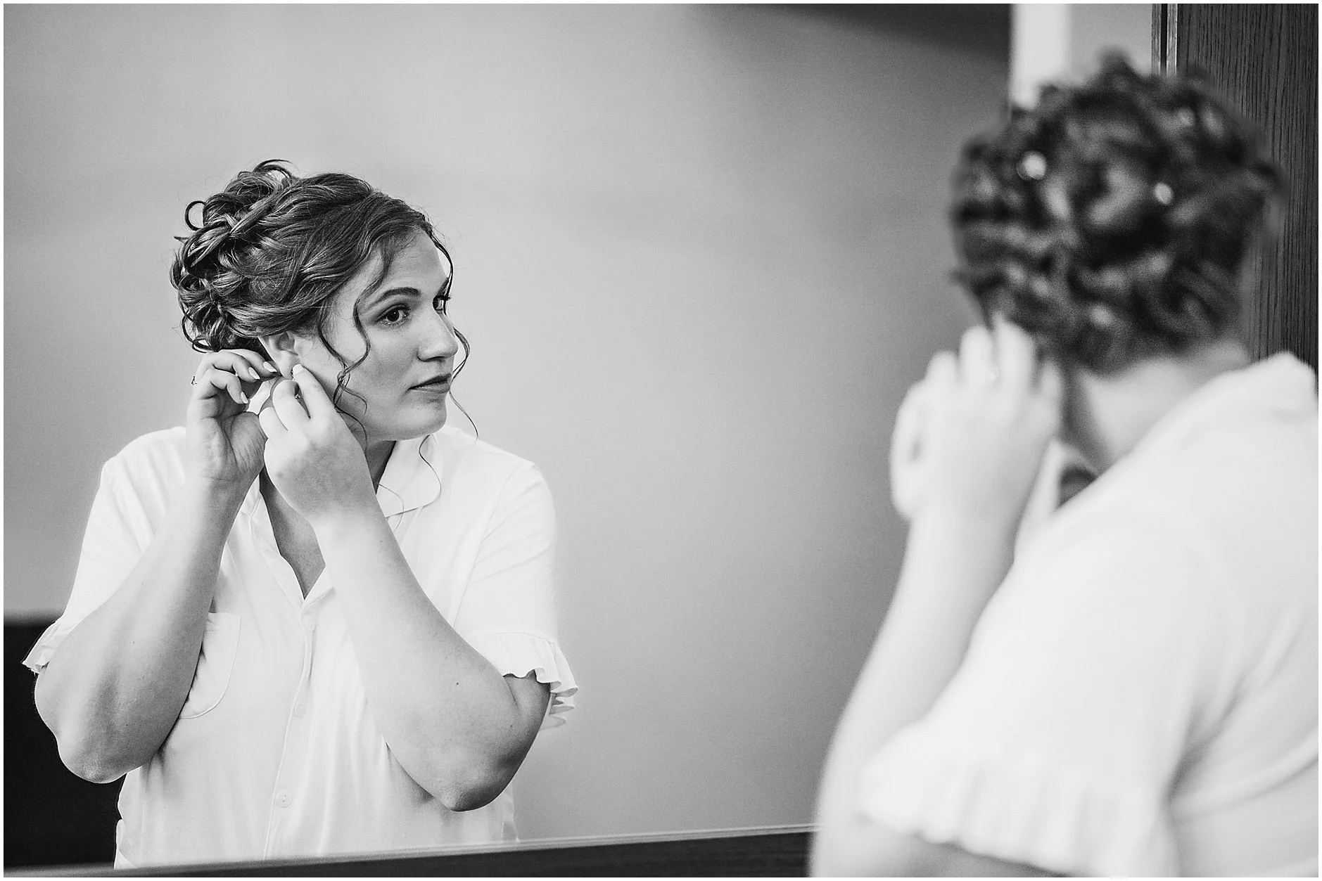 Black and white image of the bride putting her earrings in as she gets ready for her spring wedding in Upstate, NY.