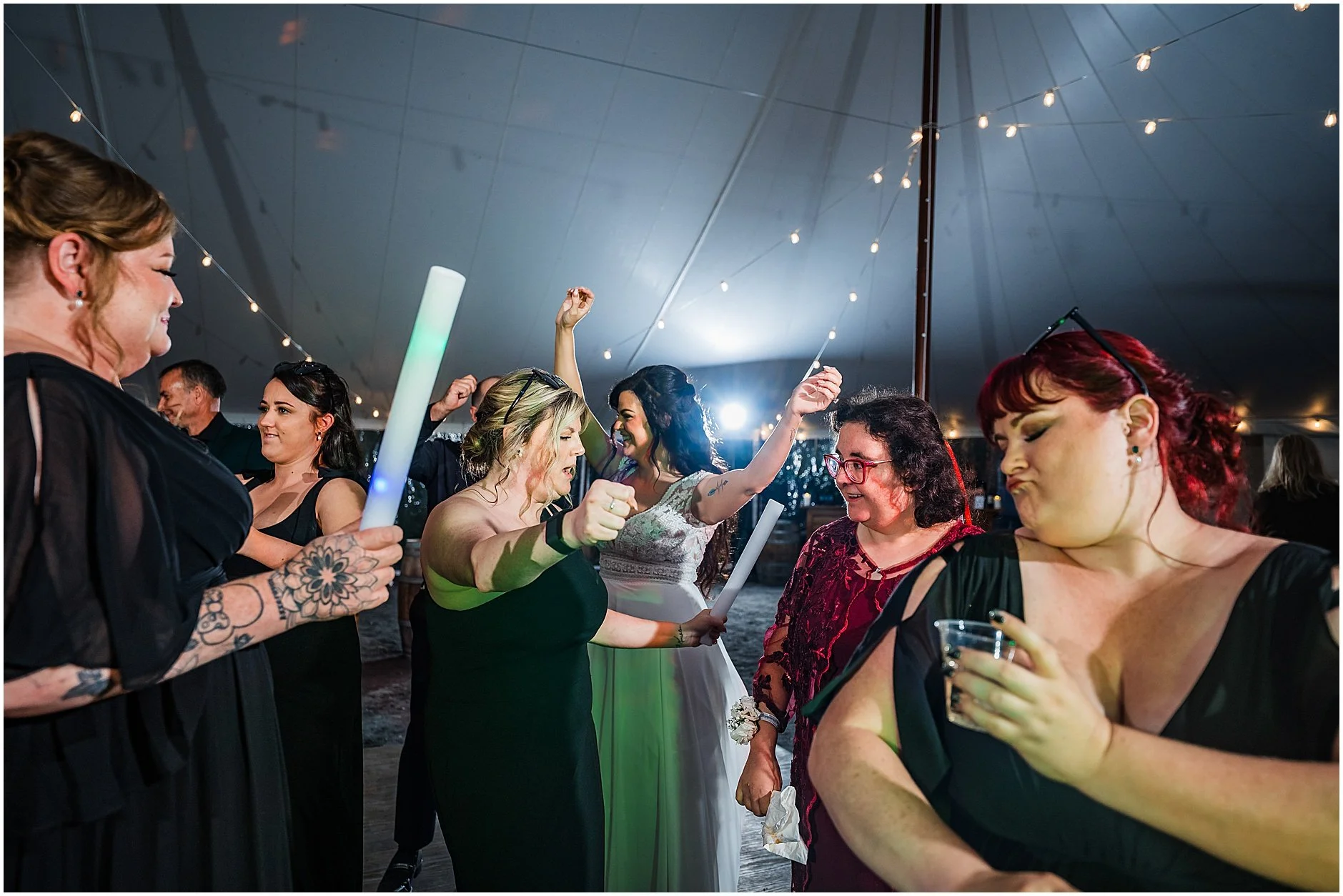 Bride dancing with her bridesmaids during wedding reception under the open sky