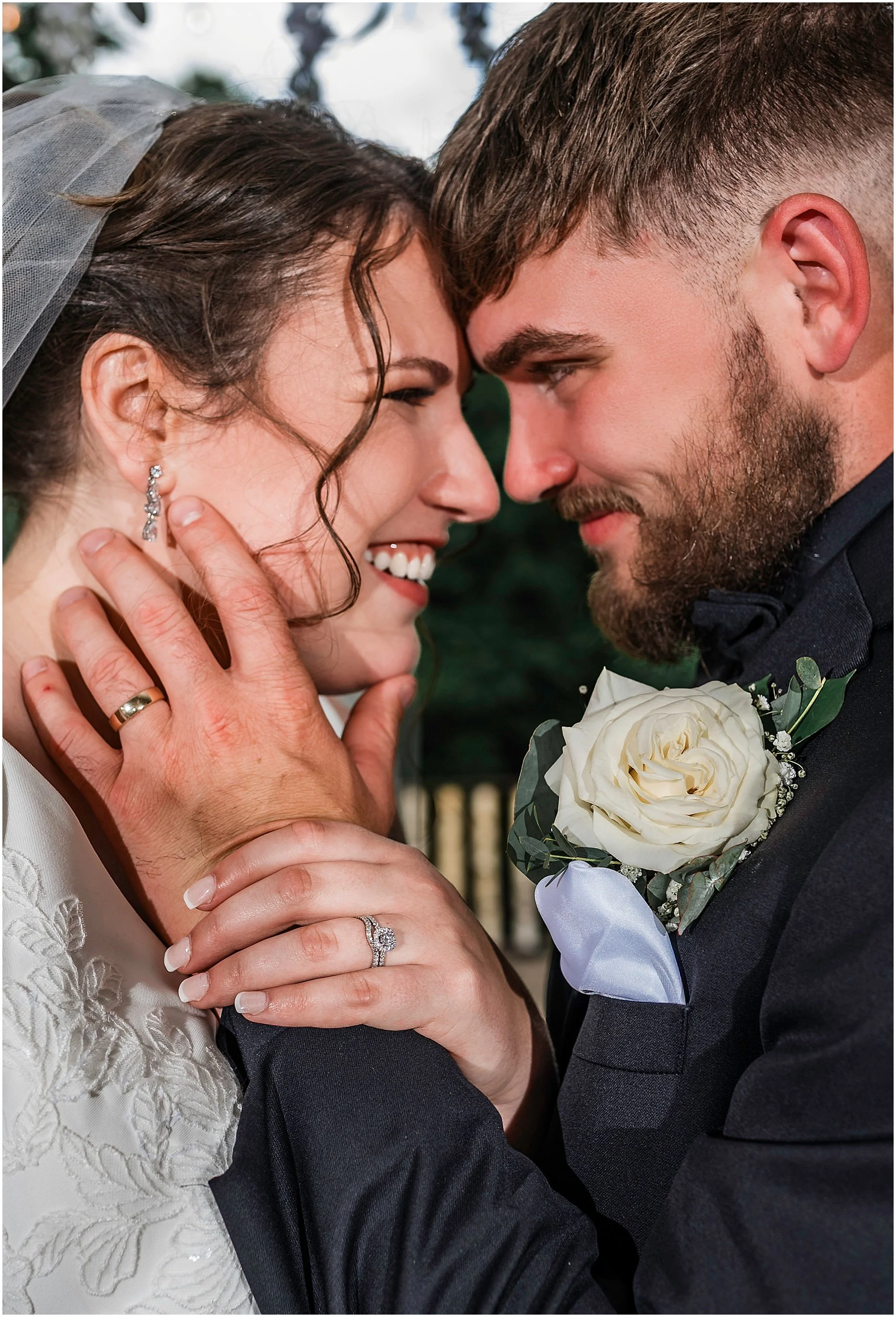 Close-up shot of the bride and groom forehead to forehead with their wedding bands showing off.