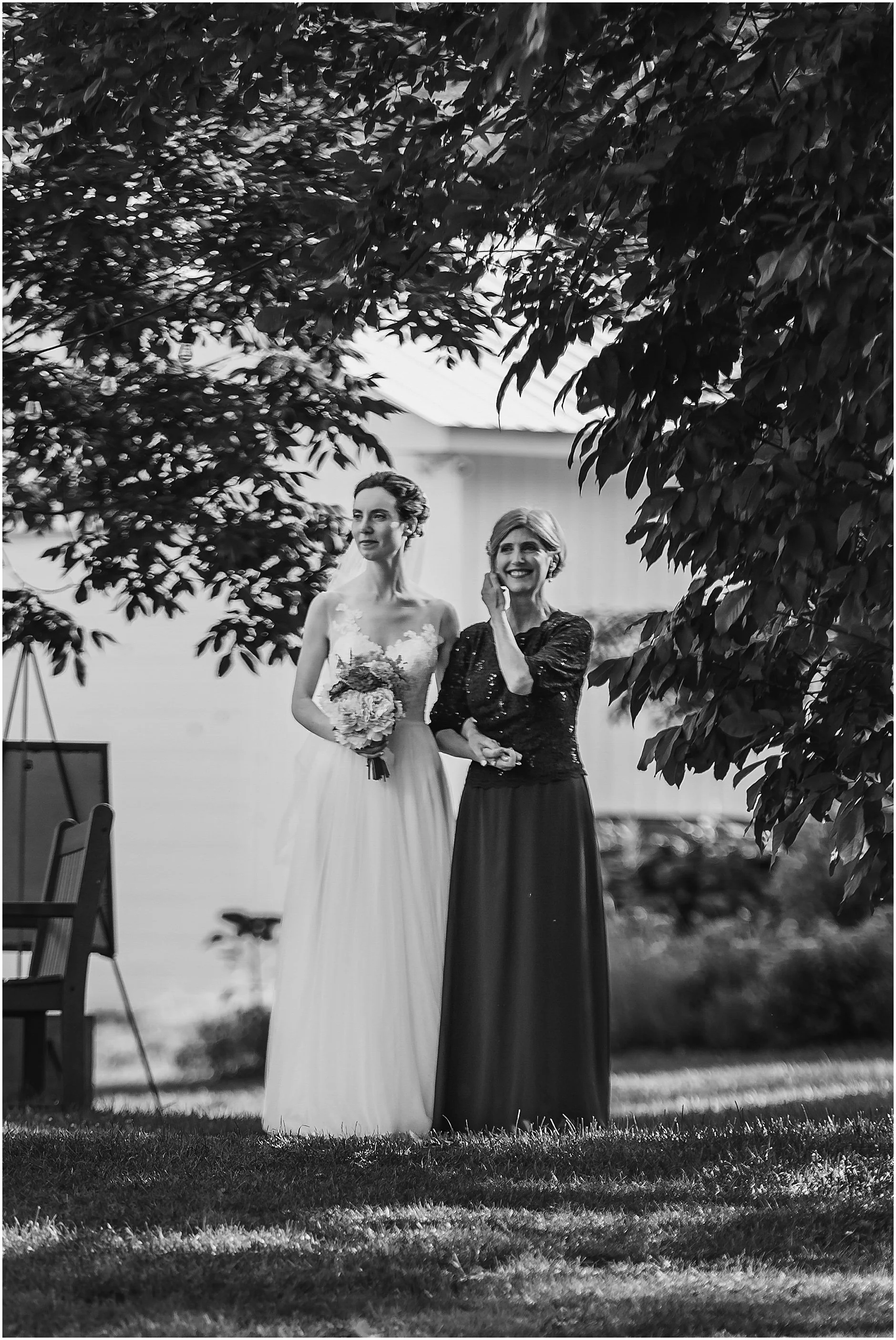 Black and white image of the bride and her mom hand in hand walking down the aisle at a Catskills NY wedding