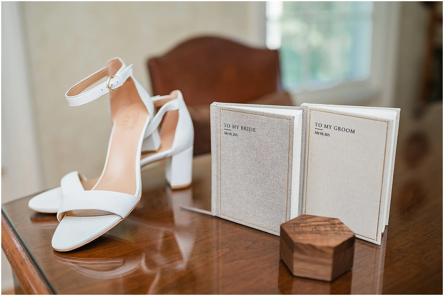 Detail shot of the bride's white high heels, the bride and groom's vow books, and the ring box