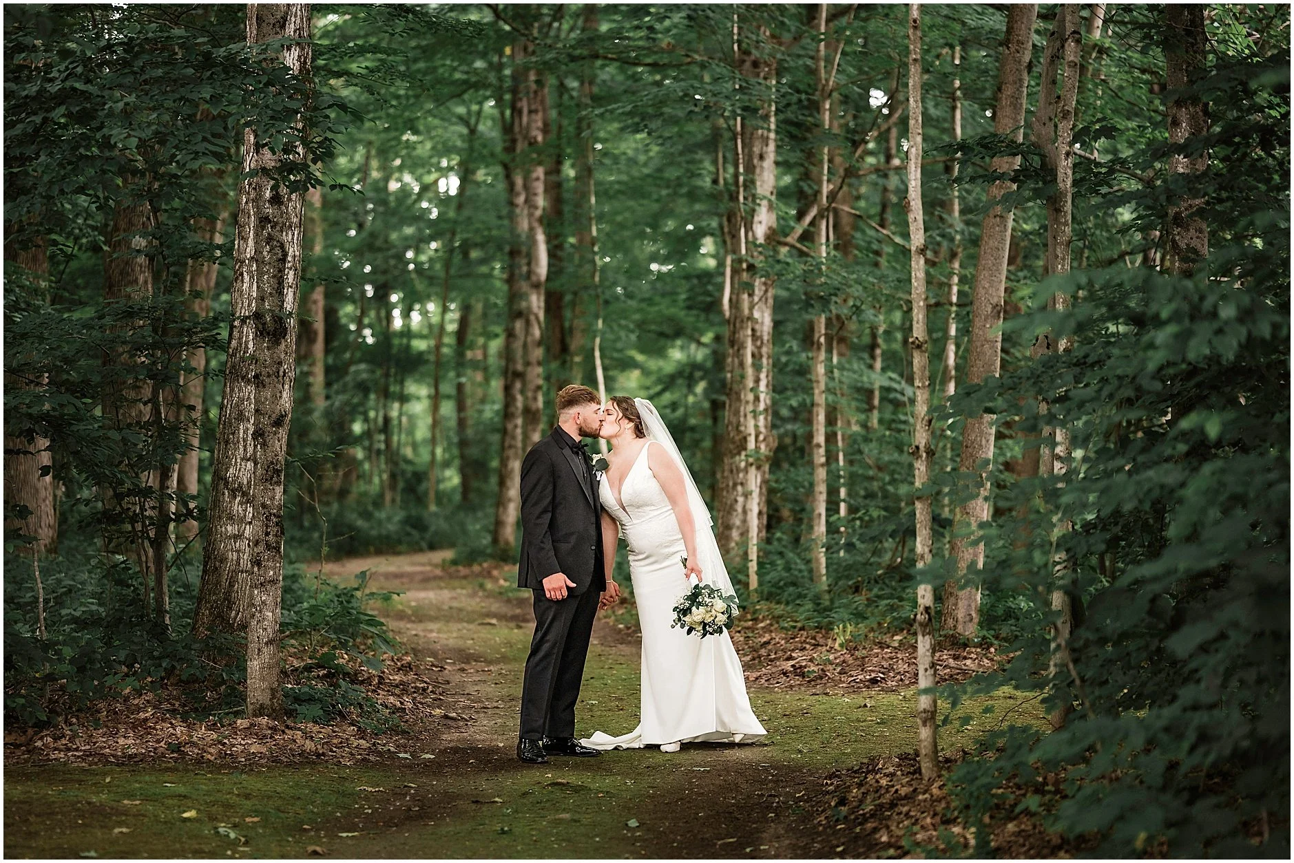 Upstate New York bride and groom sharing a kiss in the woods.