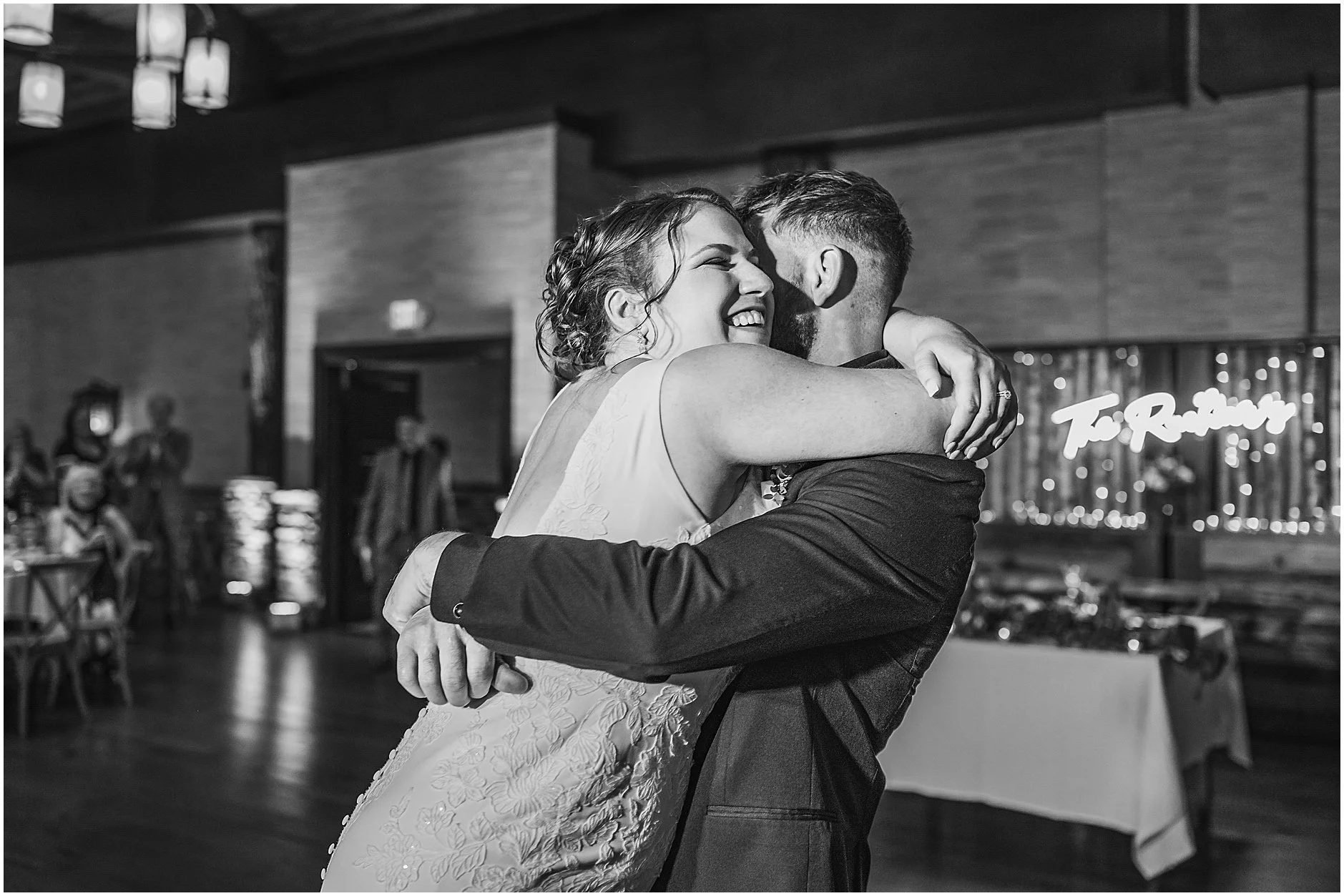 Joyful black and white photograph of an Upstate NY bride hugging her groom during their wedding reception.