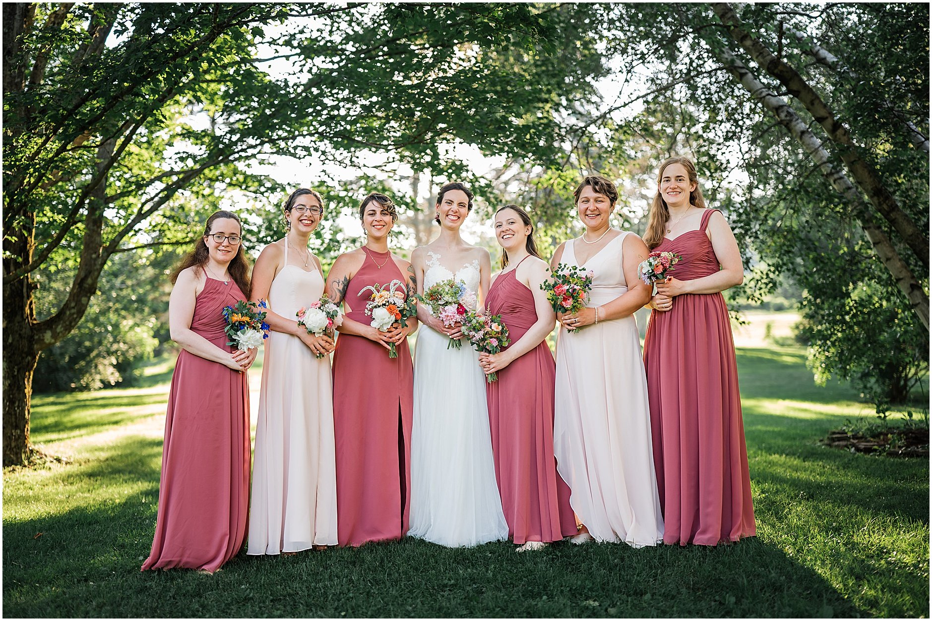Bride and her bridesmaids smiling as they pose together under the trees with golden light in the Catskill Mountains