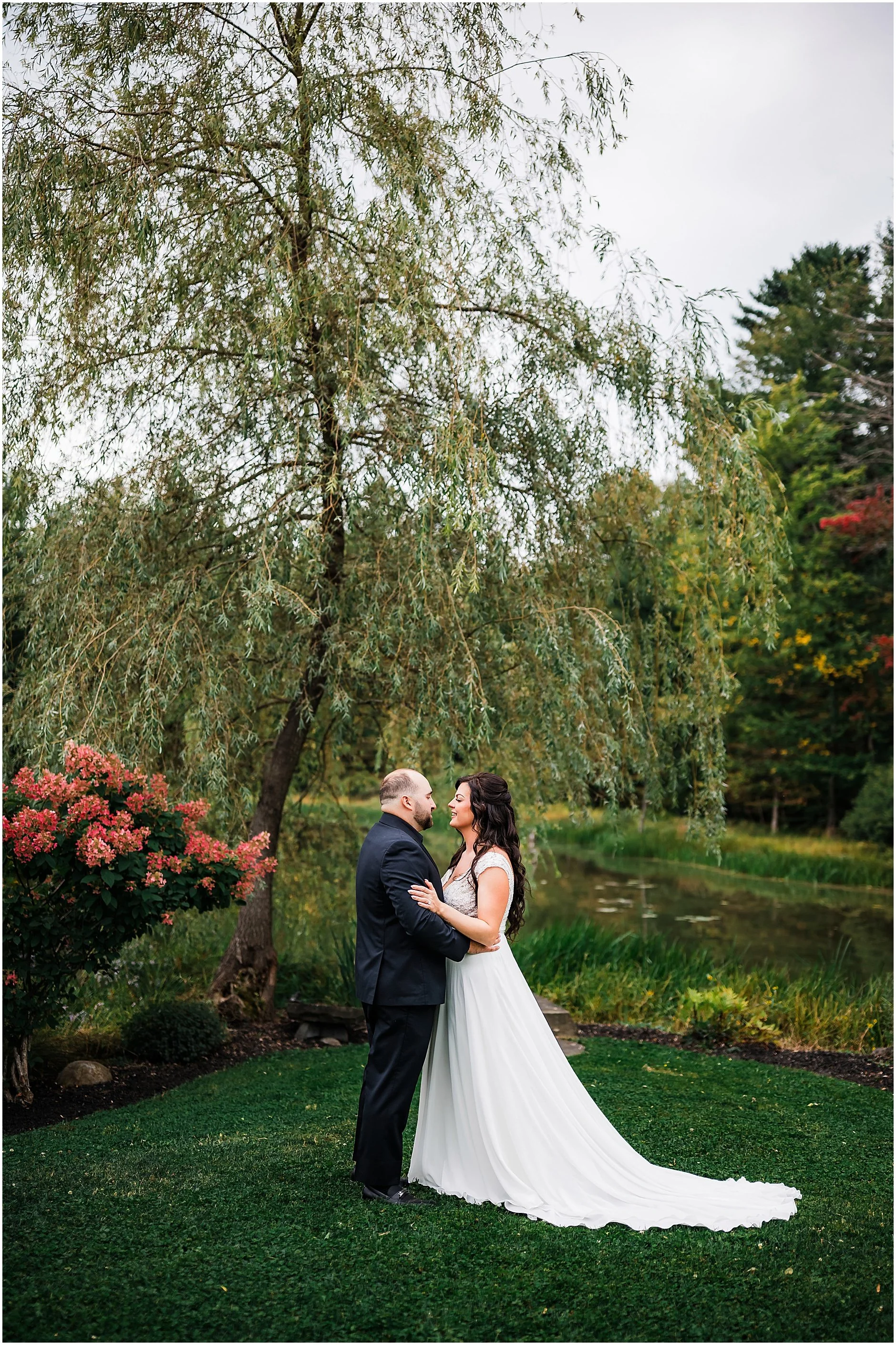 Candid portrait of bride and groom under willow tree at The Rosemary at Spano Lake in Upstate New York