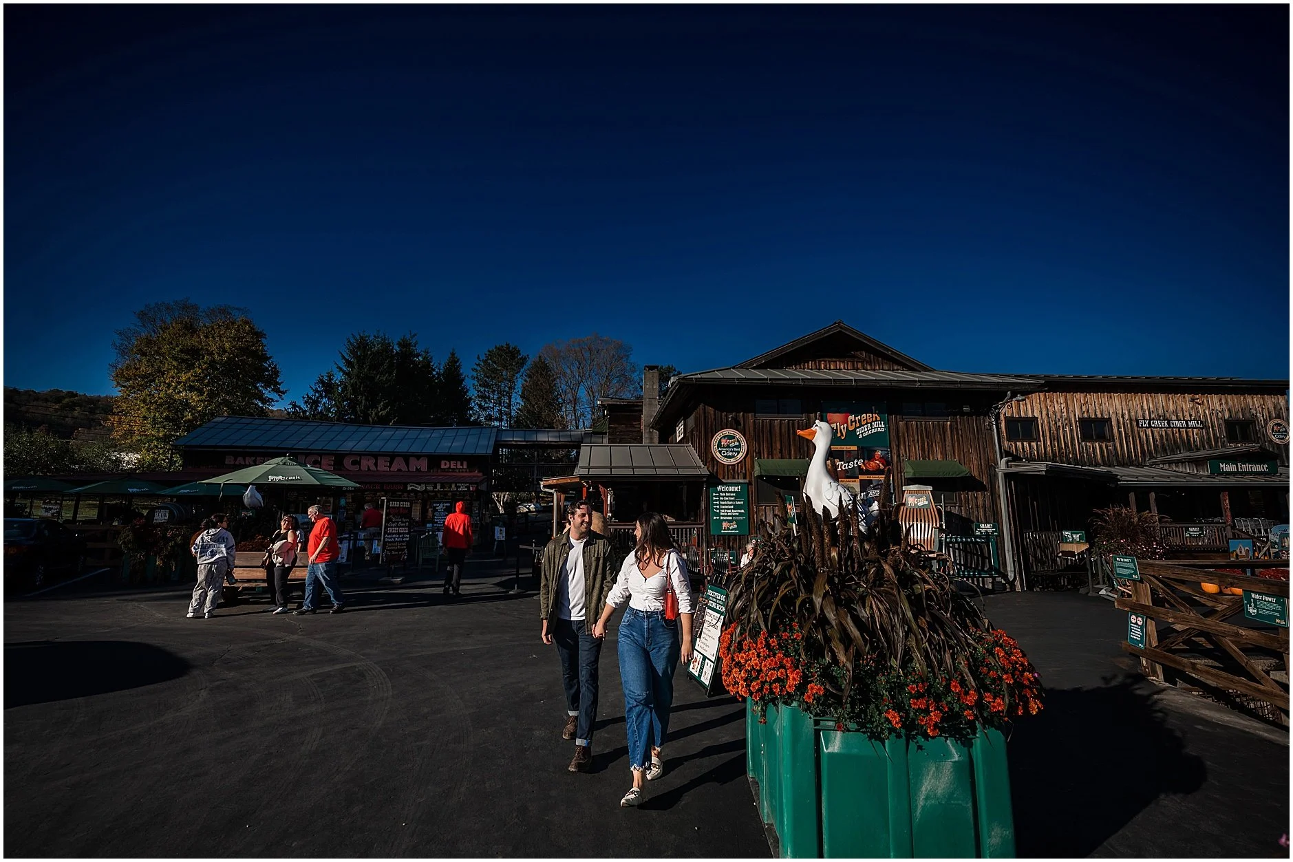 Couple walking hand in hand during downtown Cooperstown NY engagement session at the Fly Creek Cider Mill
