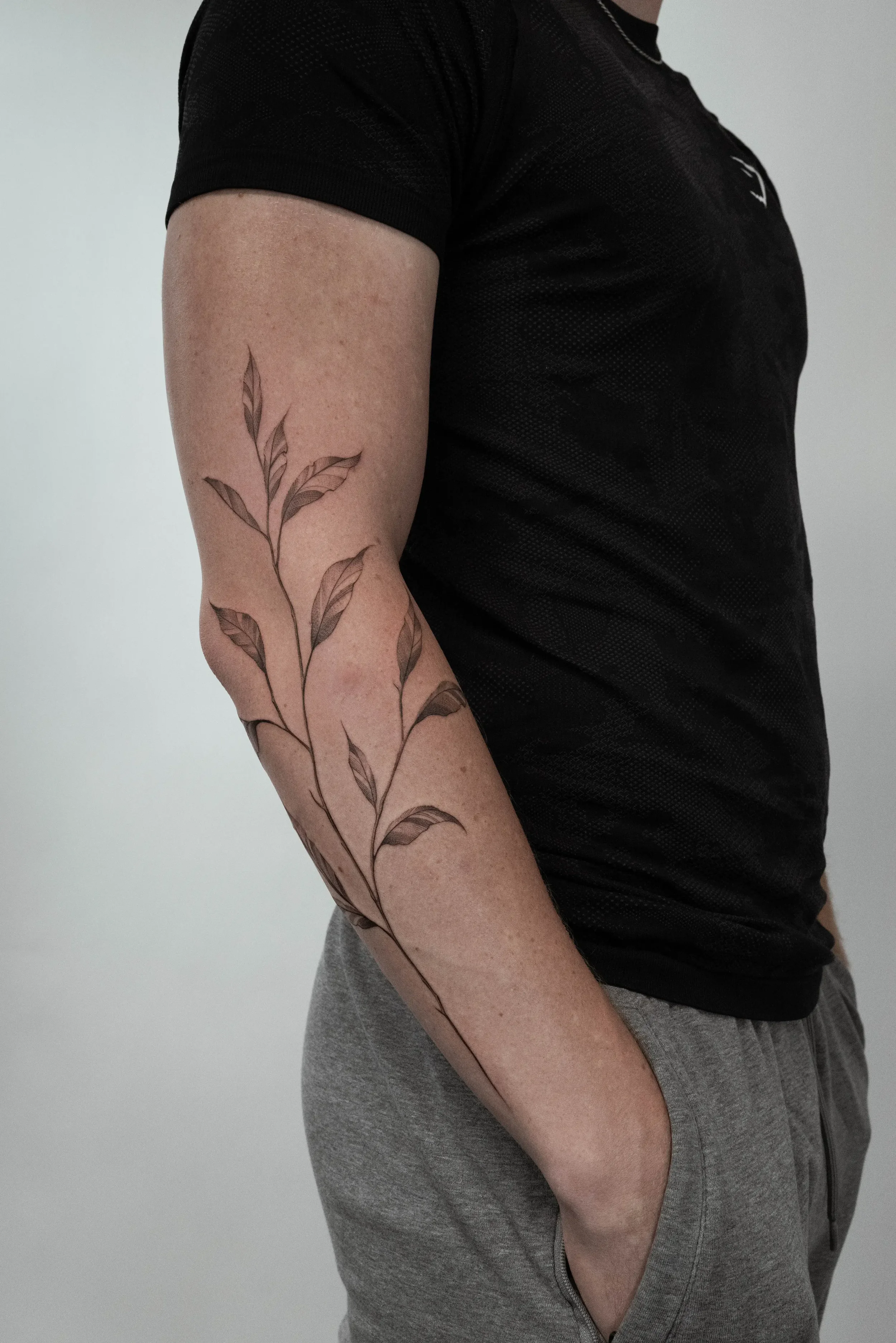 Leaves wrapping around an arm Fine Line Tattoo by Gabe Feliciano at The East Tattoo in Orlando Florida 