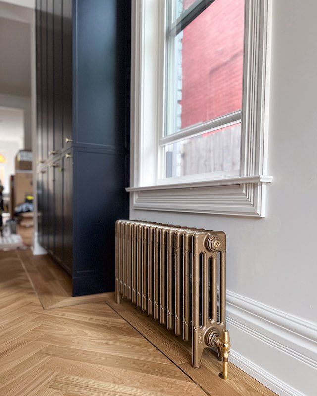 home renovations in toronto - castrad mercury radiator with herringbone flooring with brass inlay and navy blue kitchen cabinets.jpg