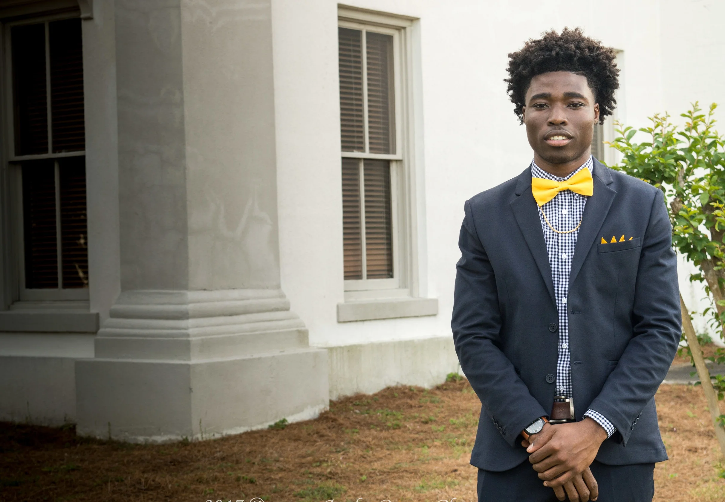 Laron in a classic dark suit, smiling in front of rustic courthouse