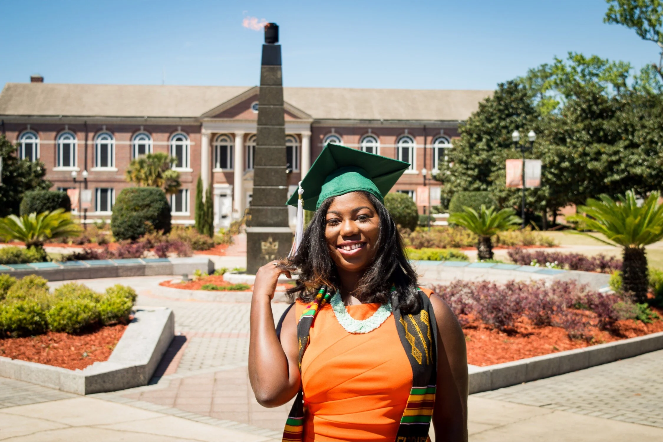  FAMU graduate Shaperlya in an orange dress at the Eternal Flame 