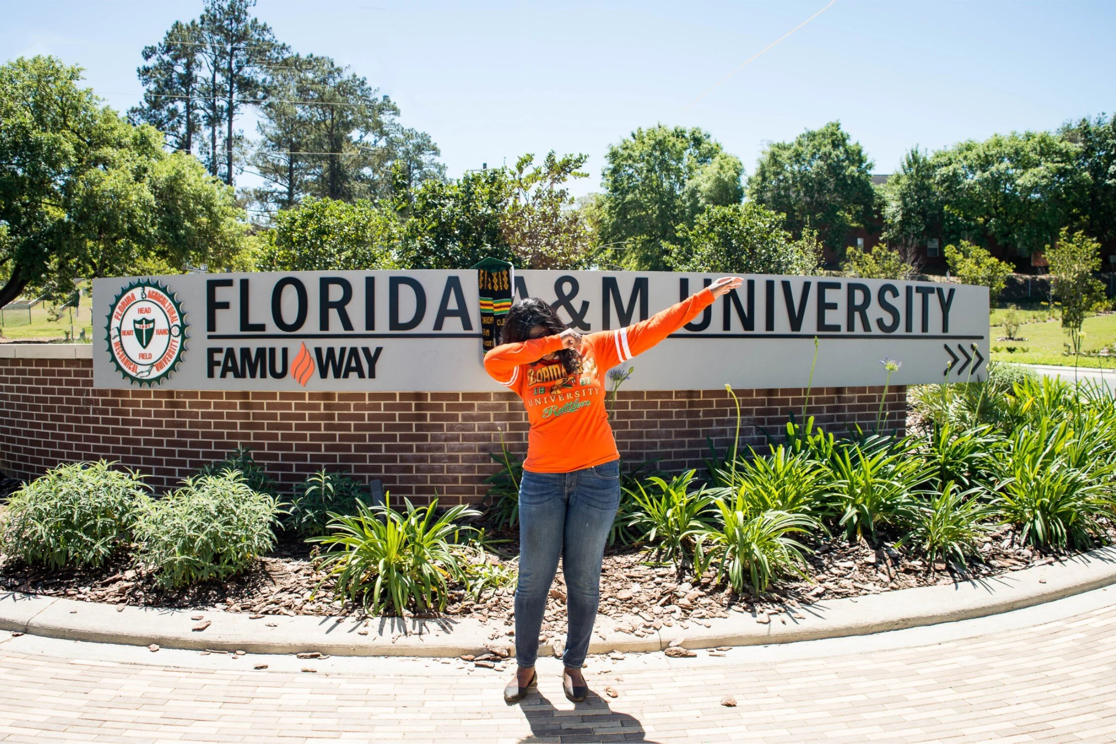  Graduate Shaperlya posing in front of new FAMU roundabout in a casual university tshirt and jeans. 