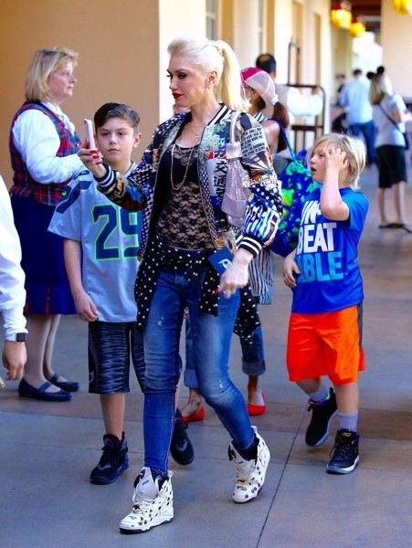 Gwen Stefani was snapped on a weekend Disney outing with her tribe wearing a Play Comme des Garcons Merino Wool Cardigan Sweater in Polka Dot, Reebok x Melody Ehsani Polka-Dot Blacktop Pump Sneakers, Dsquared2 Medium Waist Twiggy Jeans and a Libertine Japanese Print Bomber Jacket.