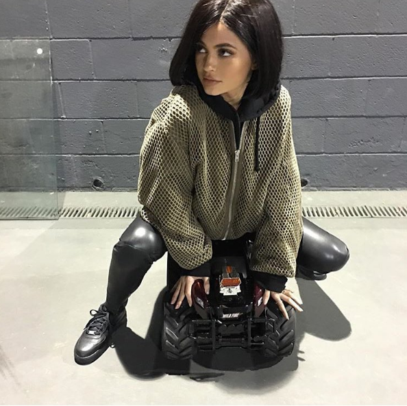 We aren't quite sure what Kylie Jenner is doing in this pose, but were definitely fangirling her olive net jacket and those blacked out Air Force 1s.