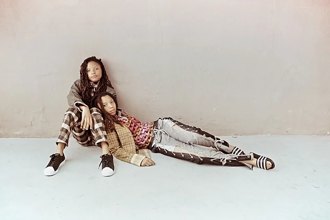 Chloe is wearing all clothes by Phlemuns, w/ Adidas slides. Halle wears Nasty Gal jacket; Adidas Superstars; and Phlemuns top, pants, and scarf.