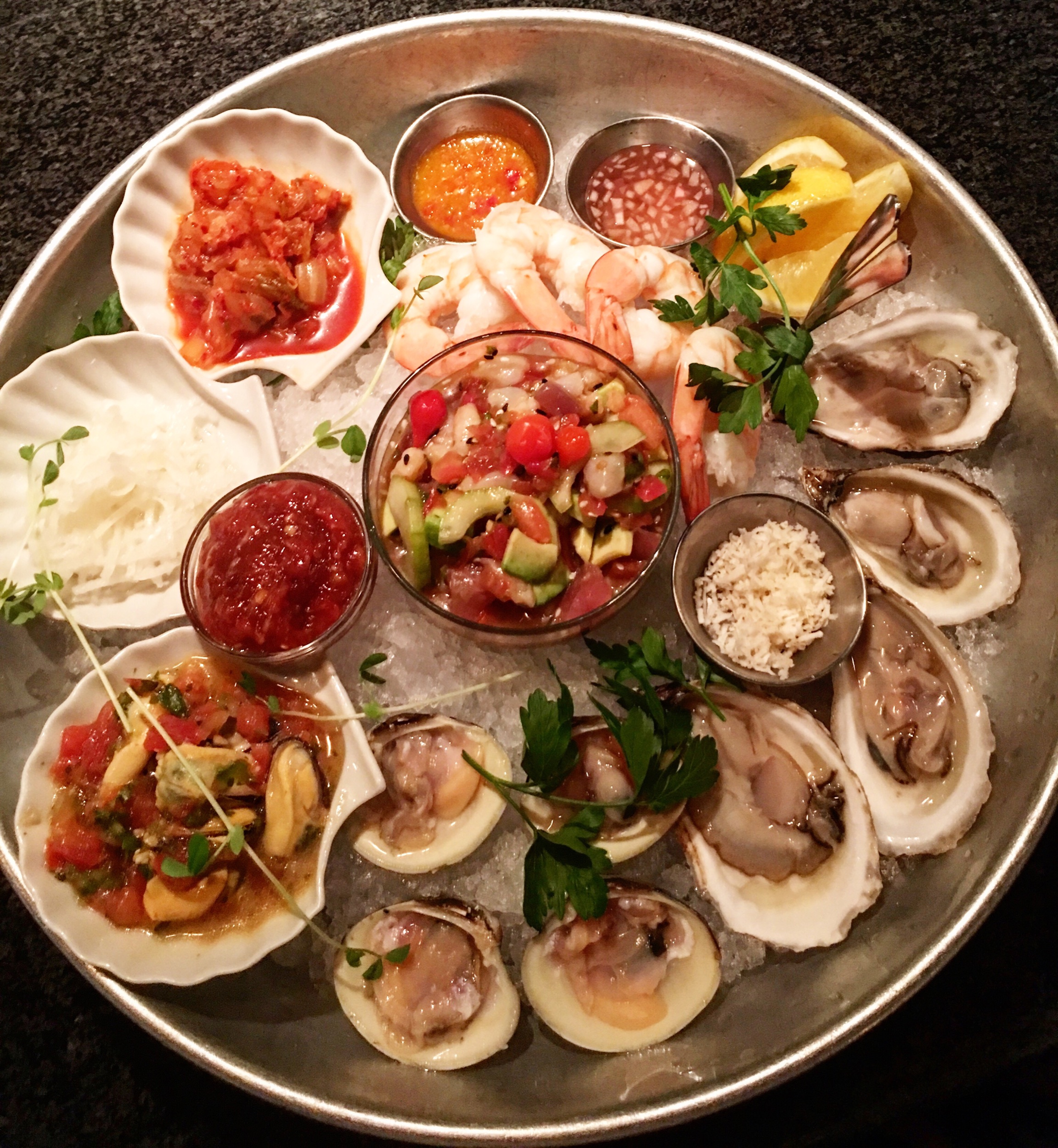Petit Plateau - iced seafood platter featuring oysters, clams, marinated mussels, shrimp, seafood poke salad, pickled daikon & kimchi.