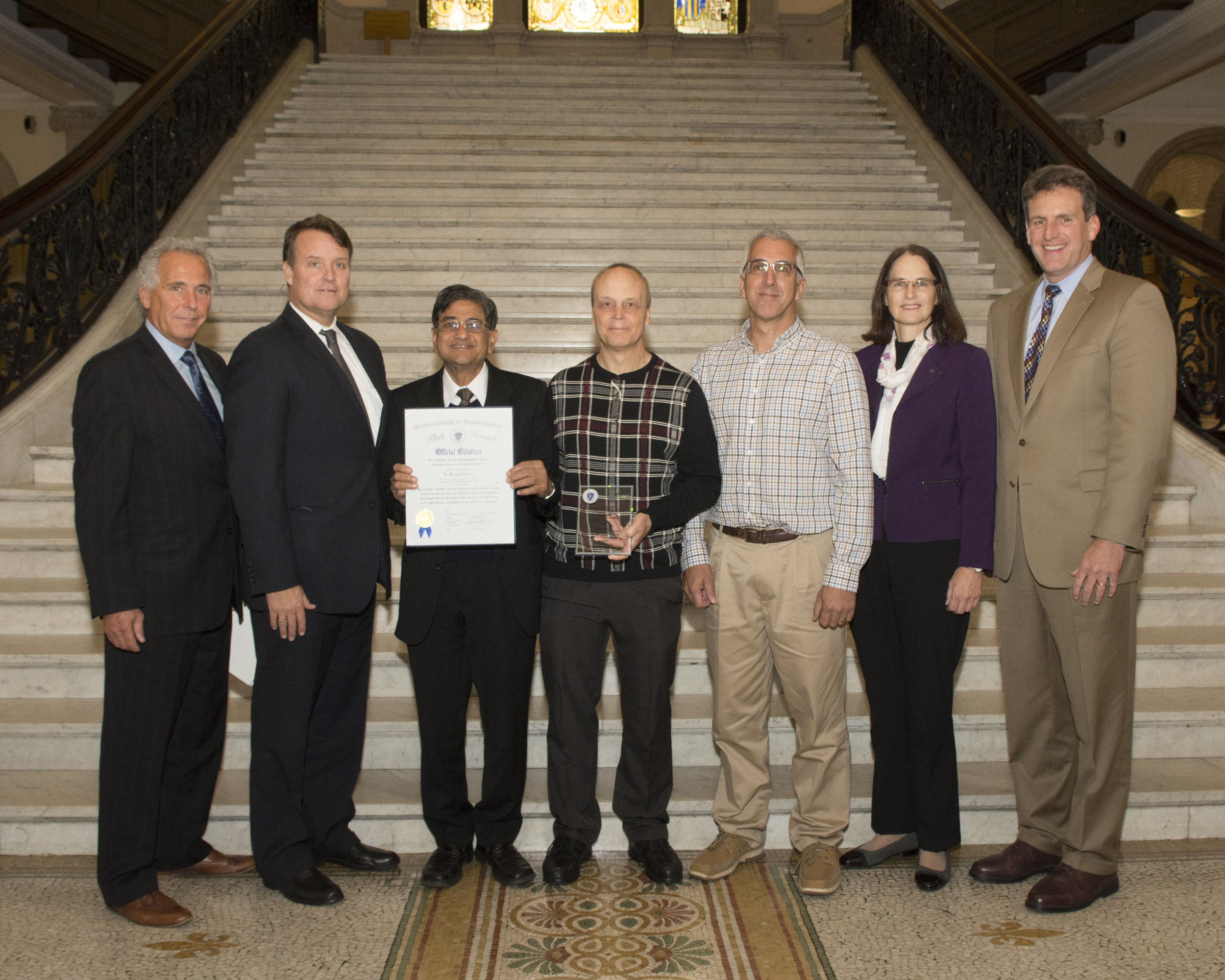 Pictured (L-R): Legislative Manufacturing Caucus House Chair, Representative John Fernandes (D-Milford), with Senator Michael Moore, Arun Basil, Will Desrosiers, Mark Penniman, Leslie Greis, Housing and Economic Development Secretary Jay Ash.