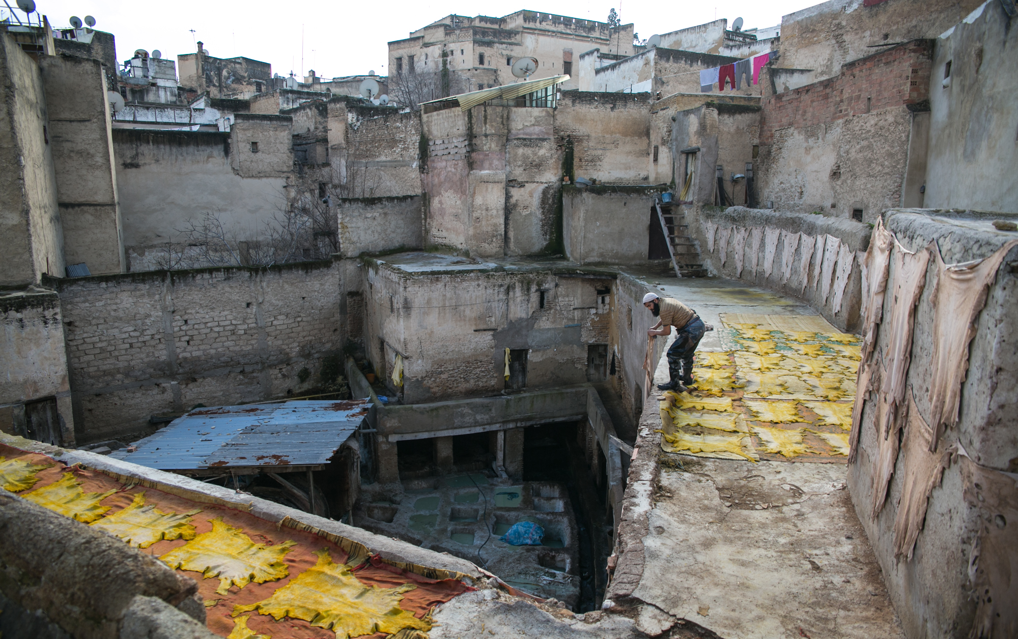 Fes, Morocco, is famous for its leather products. A worker at a leather tannery lays out dyed leather to dry. After production, finished products such as purses or shoes later make their way to the European market.
