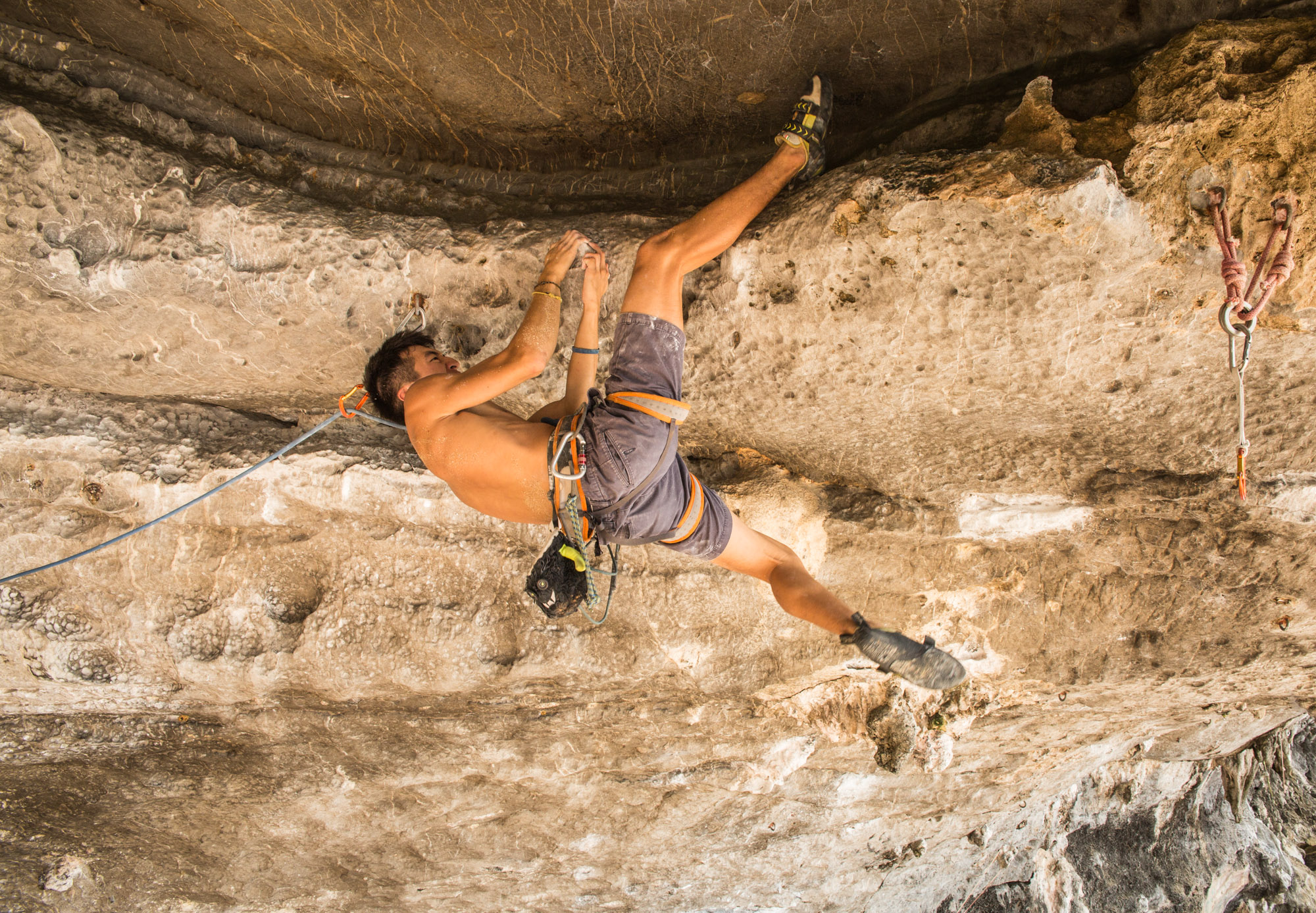 Mattias Lei on the final moves during his project climb at Tonsai Beach. During this move, he has to be very conscious of his fingertip placement and his balance while suspended from the roof as his foot is holding most of the weight.