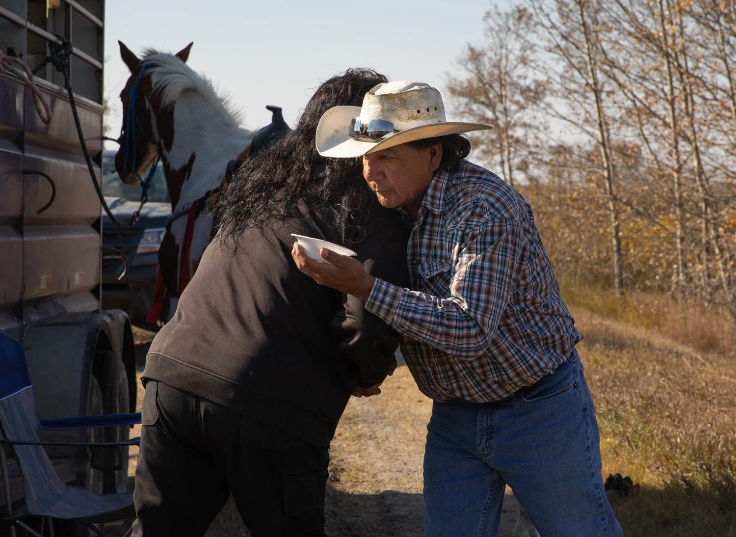  Travis hugs an attendee during a pit stop. After welcoming everyone, he is about to begin a prayer. He holds a bowl of food in one hand, a spirit dish, which is an offering to the ancestors. 