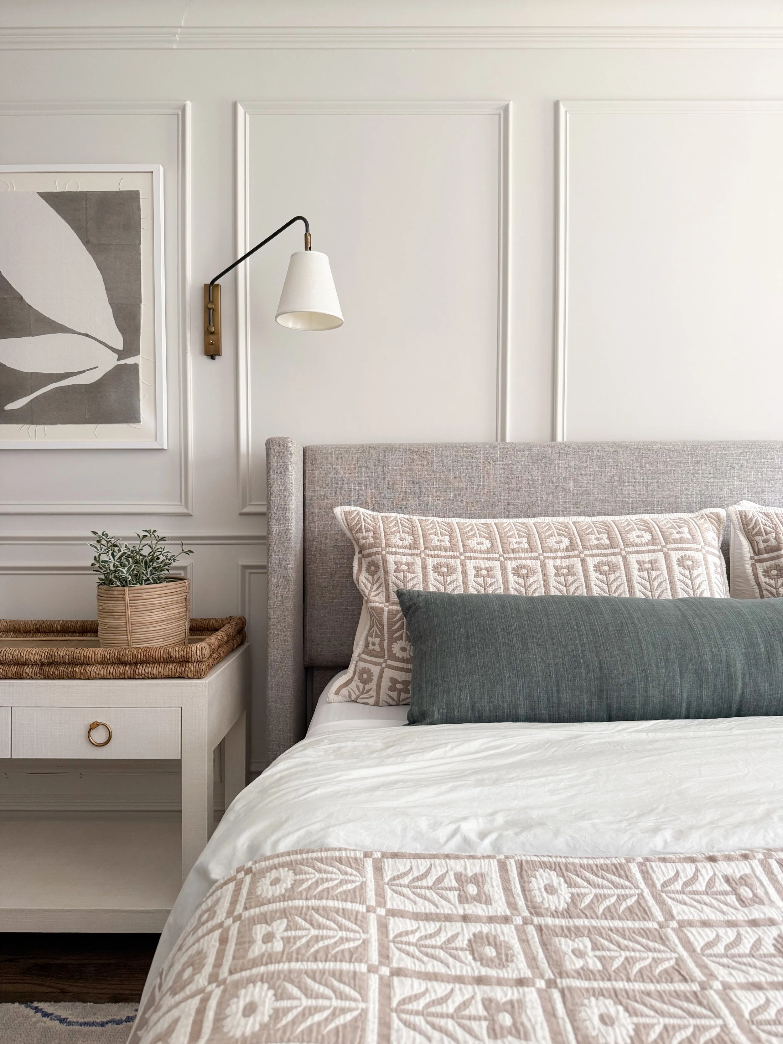 Close up of layered Quince linen bedding with quilted pillows and floral bedding details in a cozy neutral bedroom.