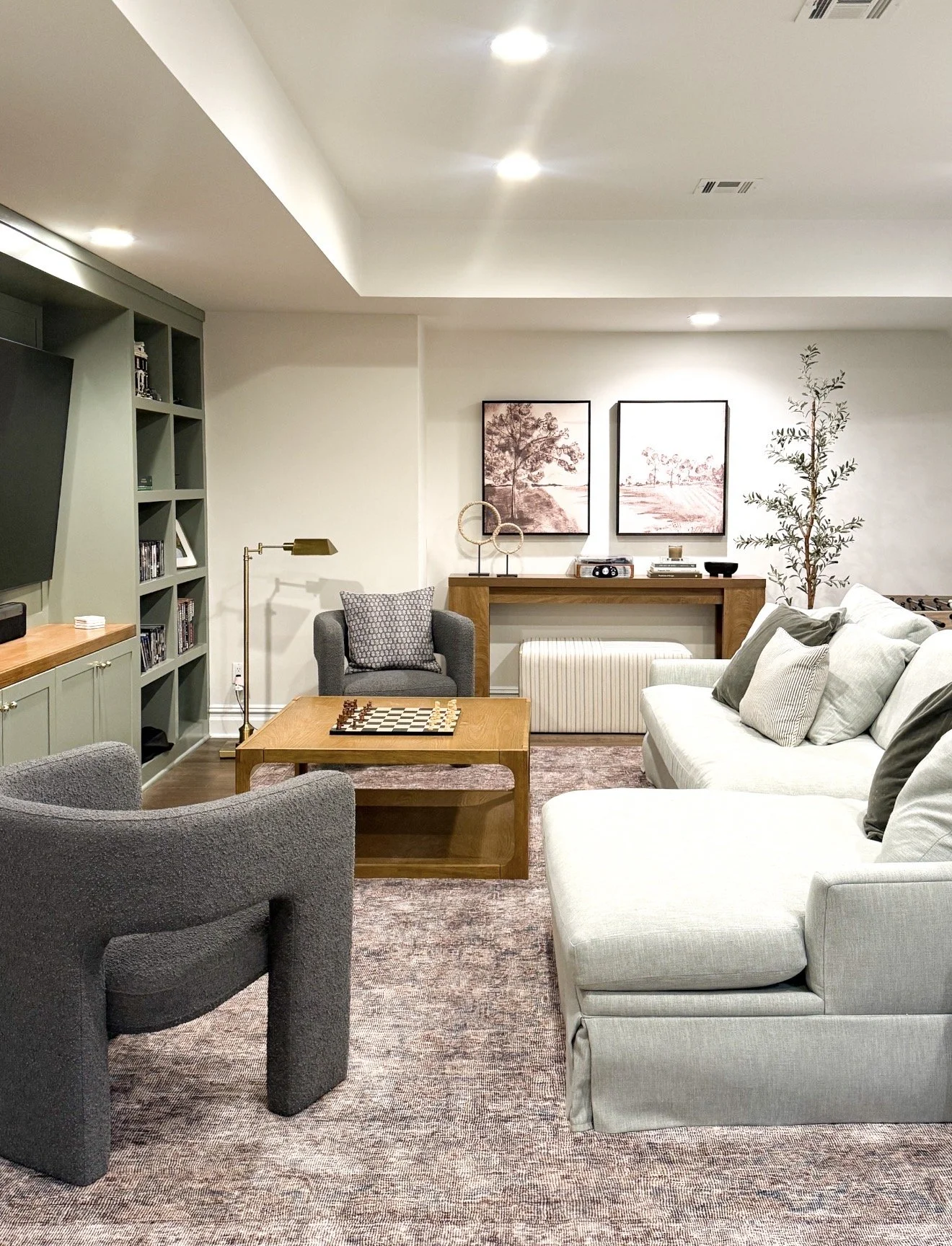 Cozy basement living room with neutral decor, sectional sofa, evergreen fog built ins and warm wood accents