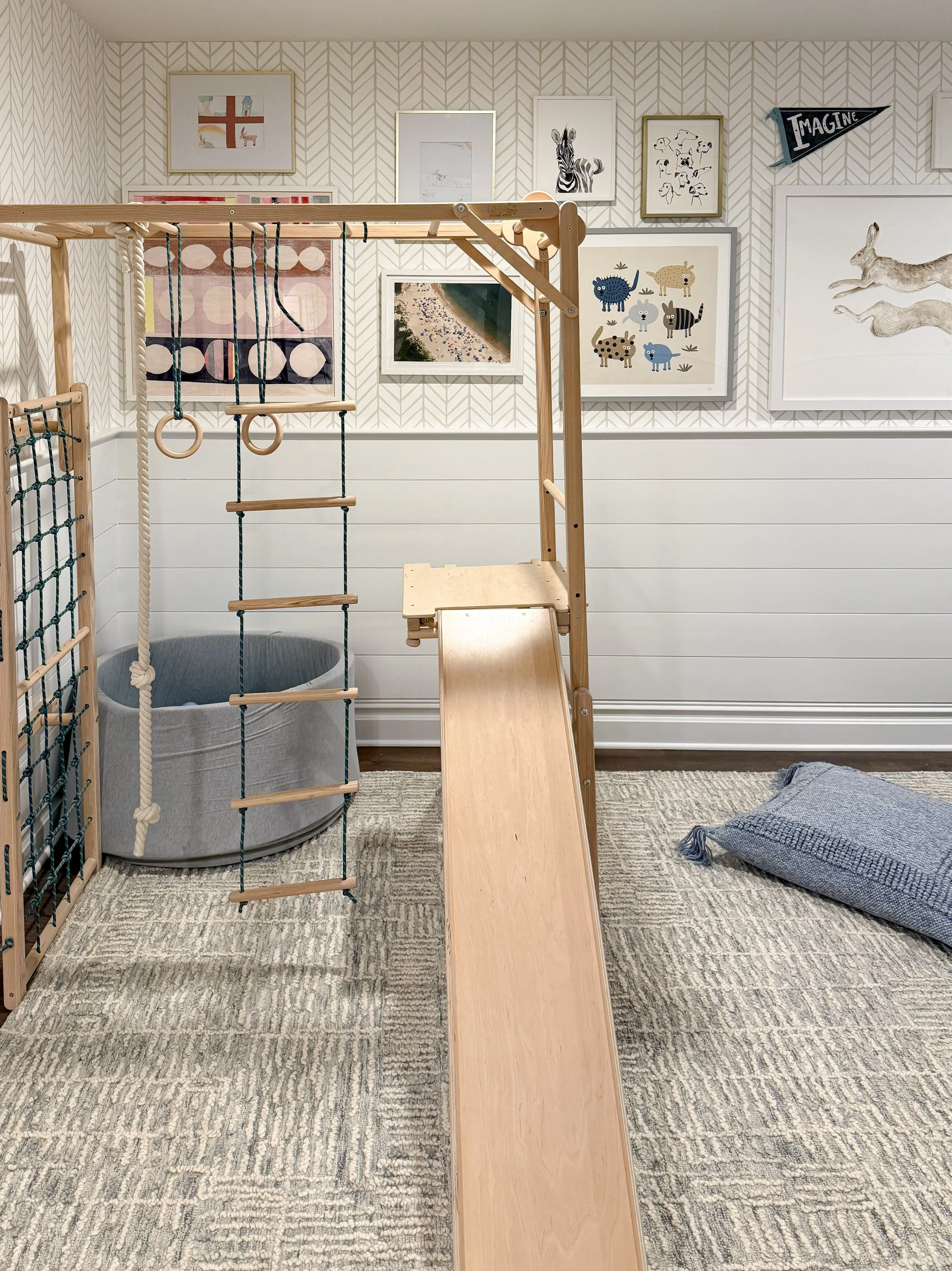 Bright playroom with indoor climbing gym, neutral area rug, wood toys, and family friendly décor.